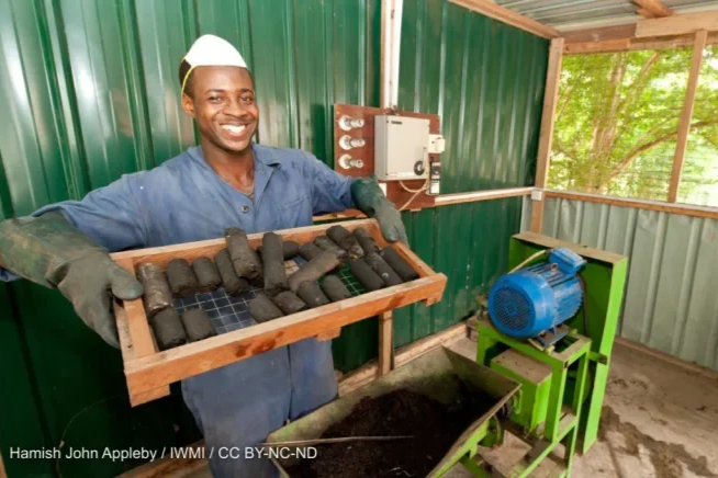 Farmer holding up tray of Briquette press in Ghana