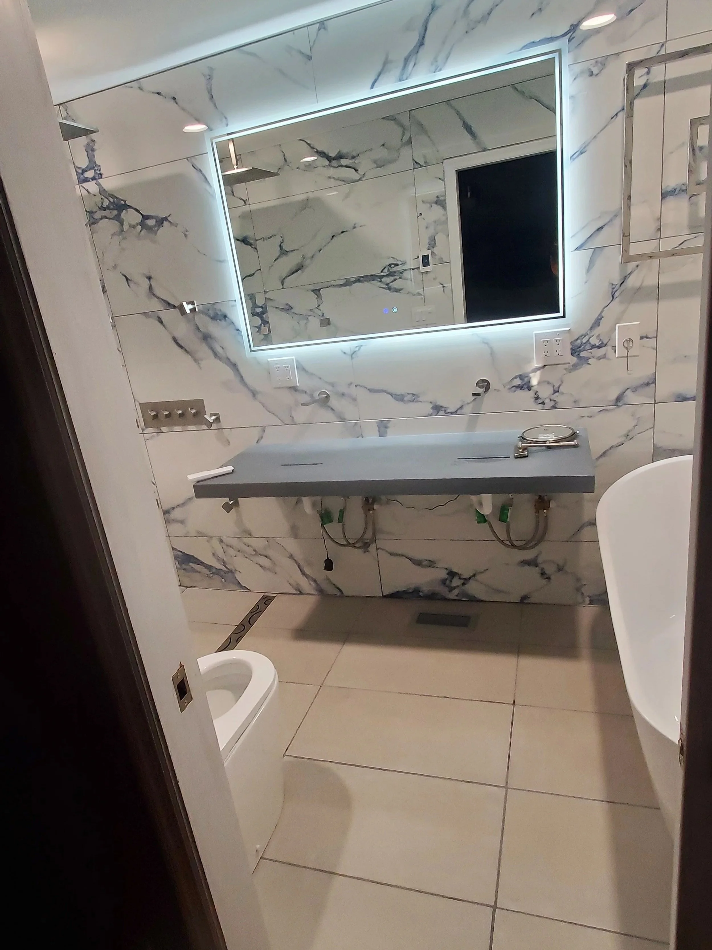 Master bath renovation in Chattanooga, TN showing heated floor, custom concrete sink, lighted mirror and tile wall