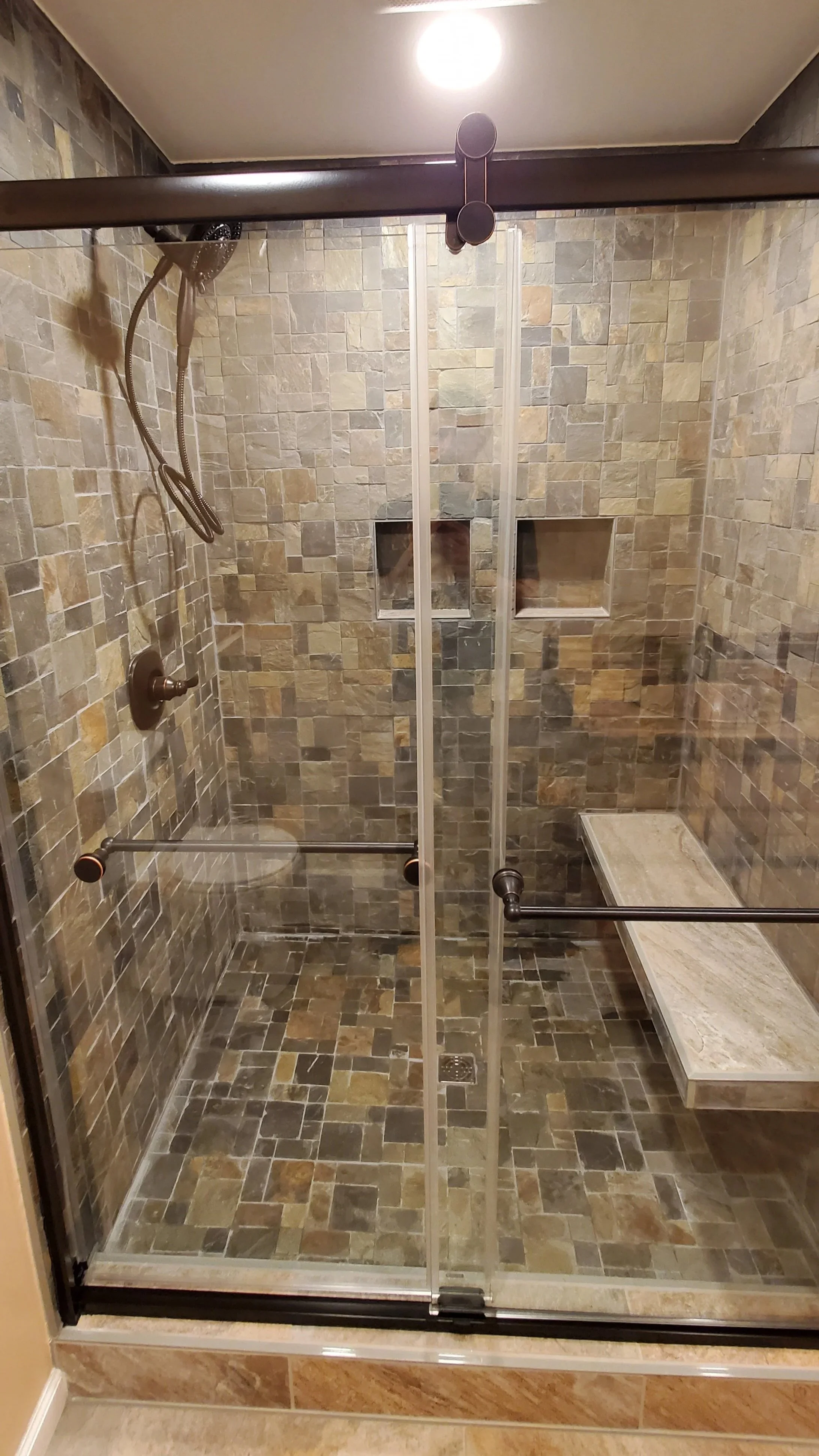 Basement bathroom in East TN stone shower with floating bench and niches