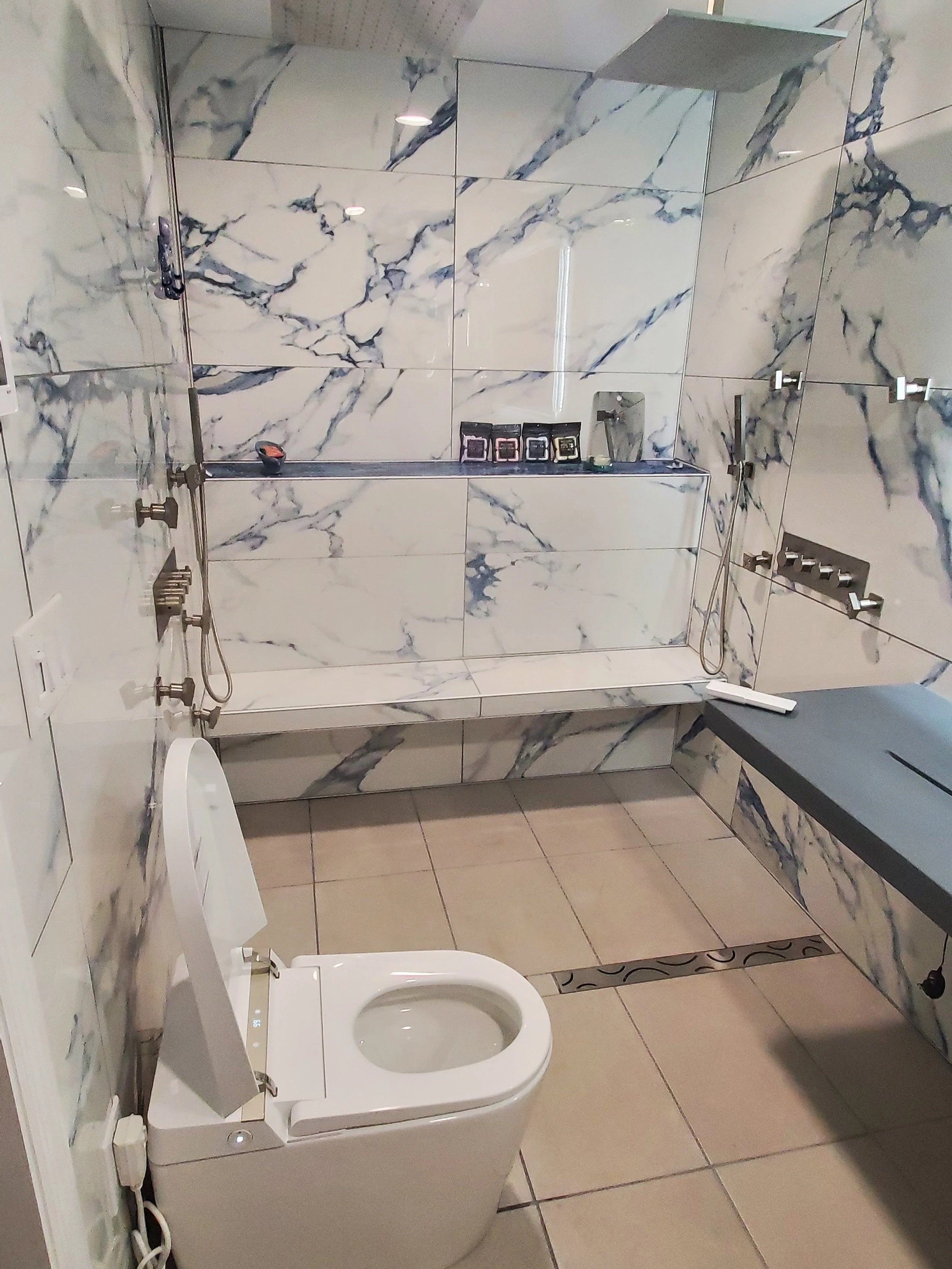 Master bathroom renovation in Chattanooga, TN, showing custom heated bench, heated floors, shower system, curbless shower, toilet/bidet with heated seat