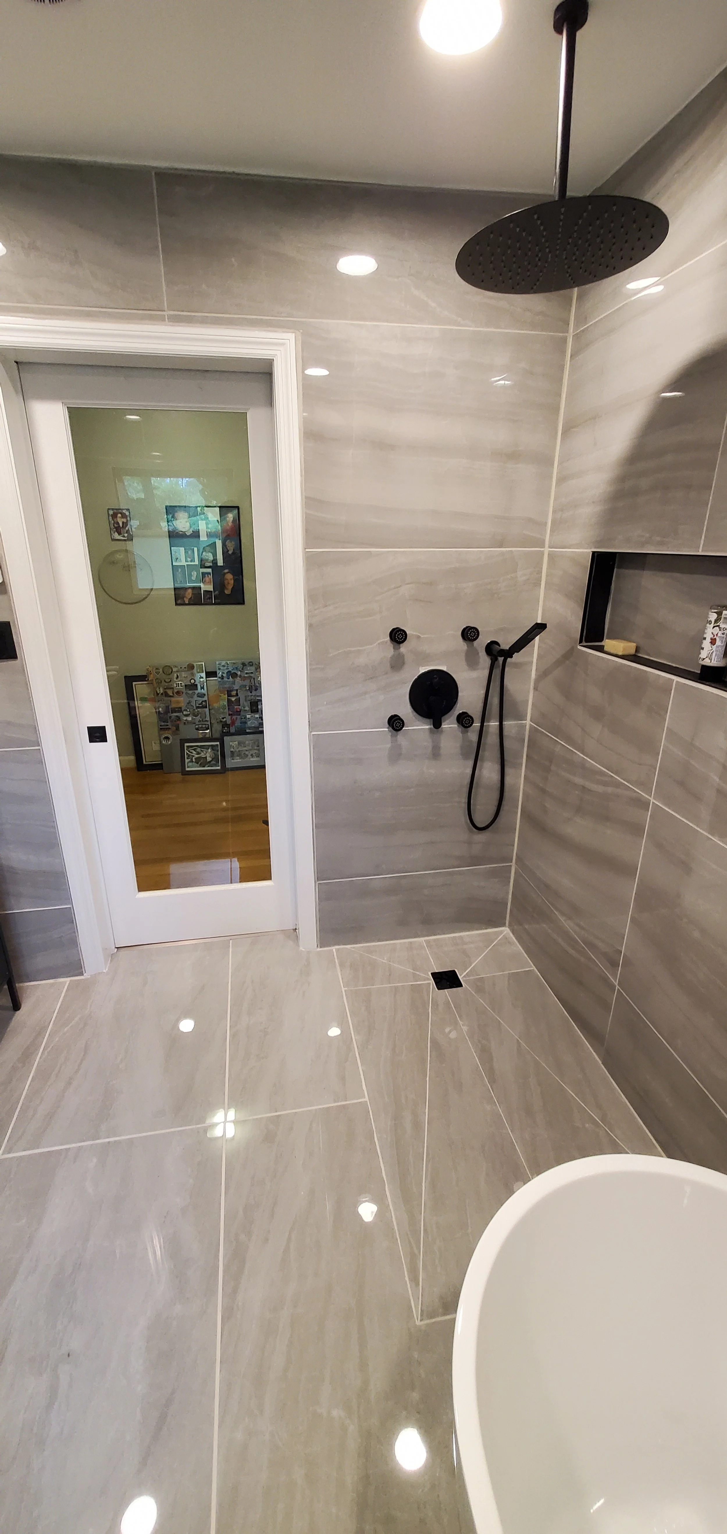 Guest bathroom remodel in Chattanooga, TN showing walk-in shower with heated floor and built-in-niche, custom shower body spray system, and new entry door