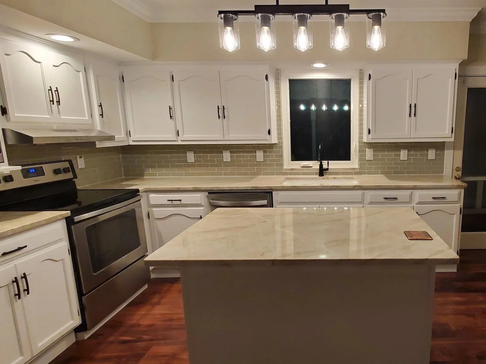 Kitchen renovation in Cleveland,, TN showing custom island with popup outlet, new counters and backsplash, refinished cabinets, LVP floor