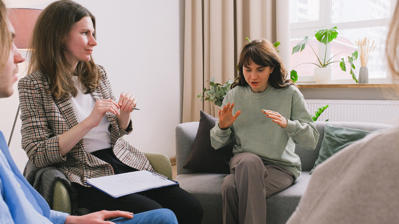 Small group of therapists in conversation during an EMDR consultation group, one holding a clipboard as a colleague shares