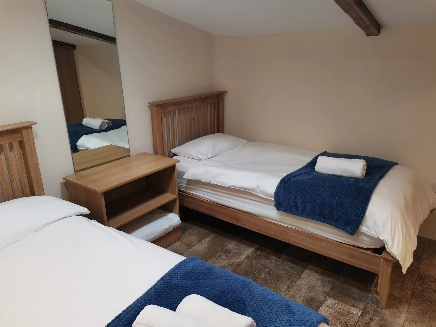 Fairy River cottage bedroom with wooden beds, white bedding and navy throws