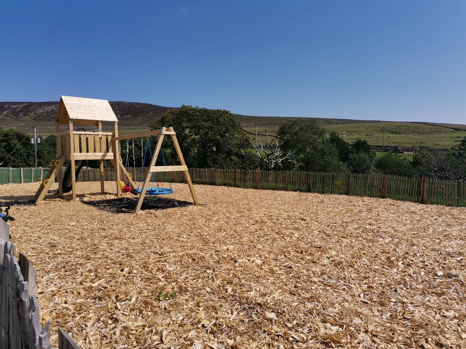 Swings and a timber play tower with the Mourne Mountains in the background