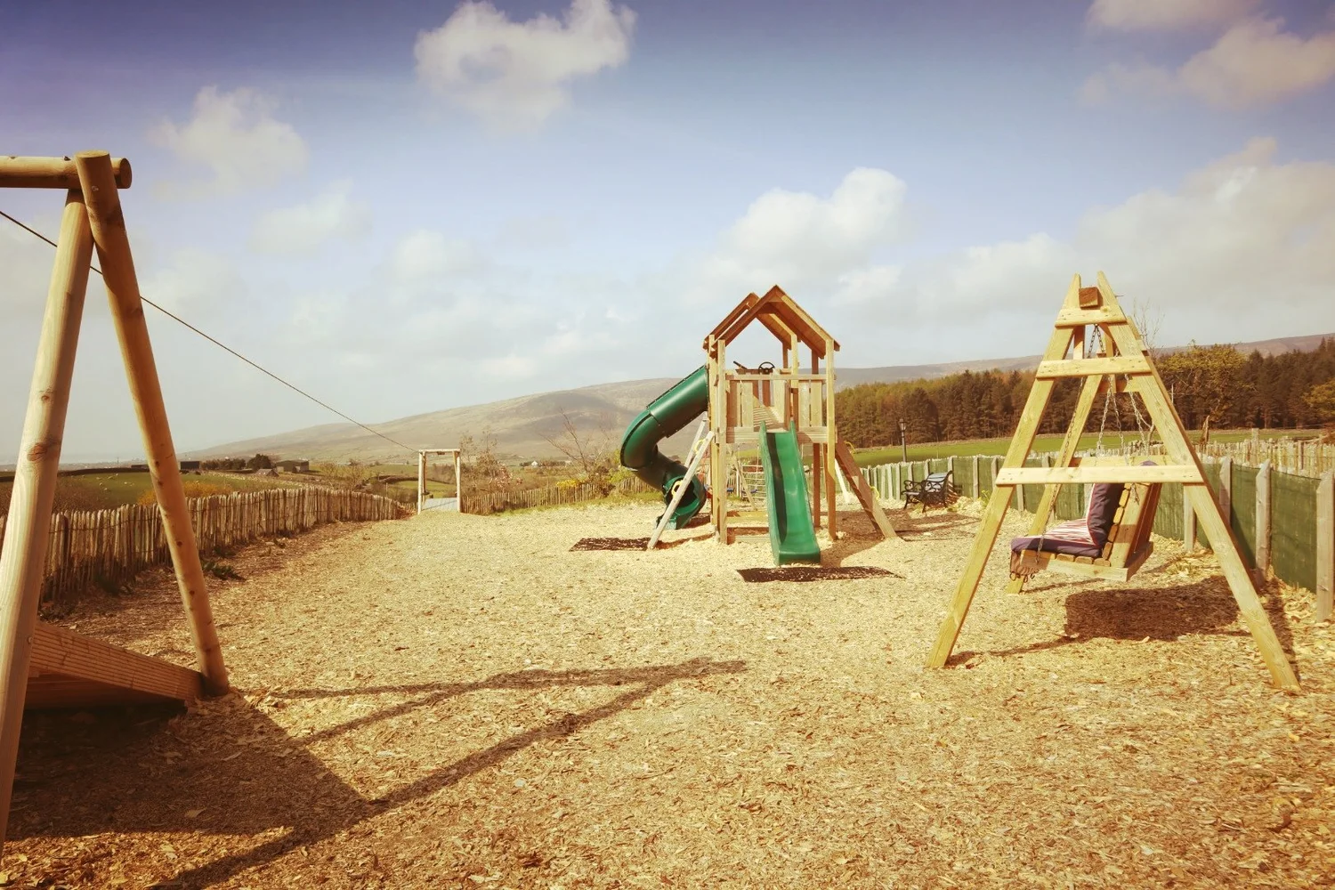 Timber climbing frames, green slides and a zip line at the Fairy River playpark