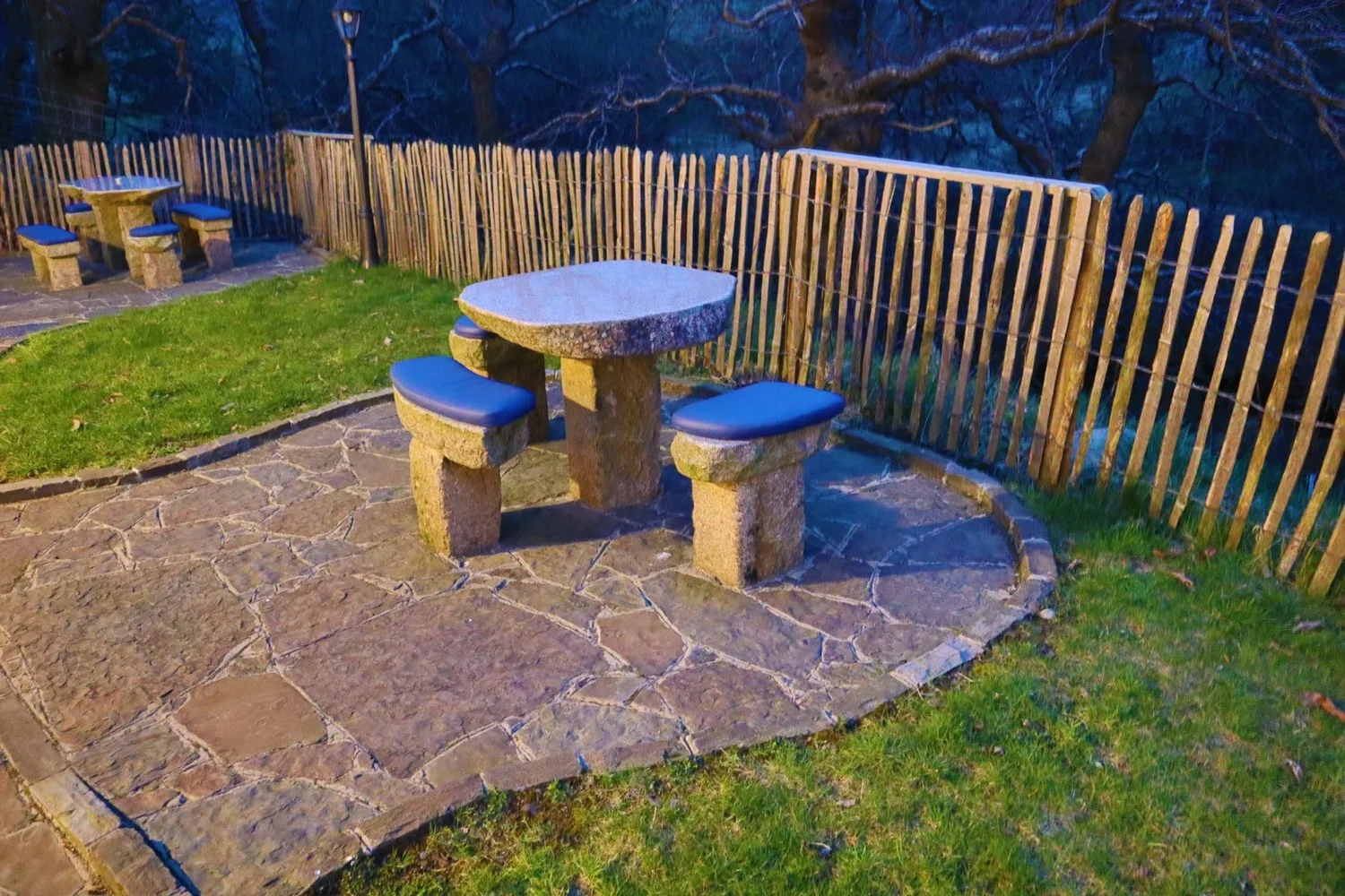 Stone table and seating on a Fairy River cottage patio beside the garden