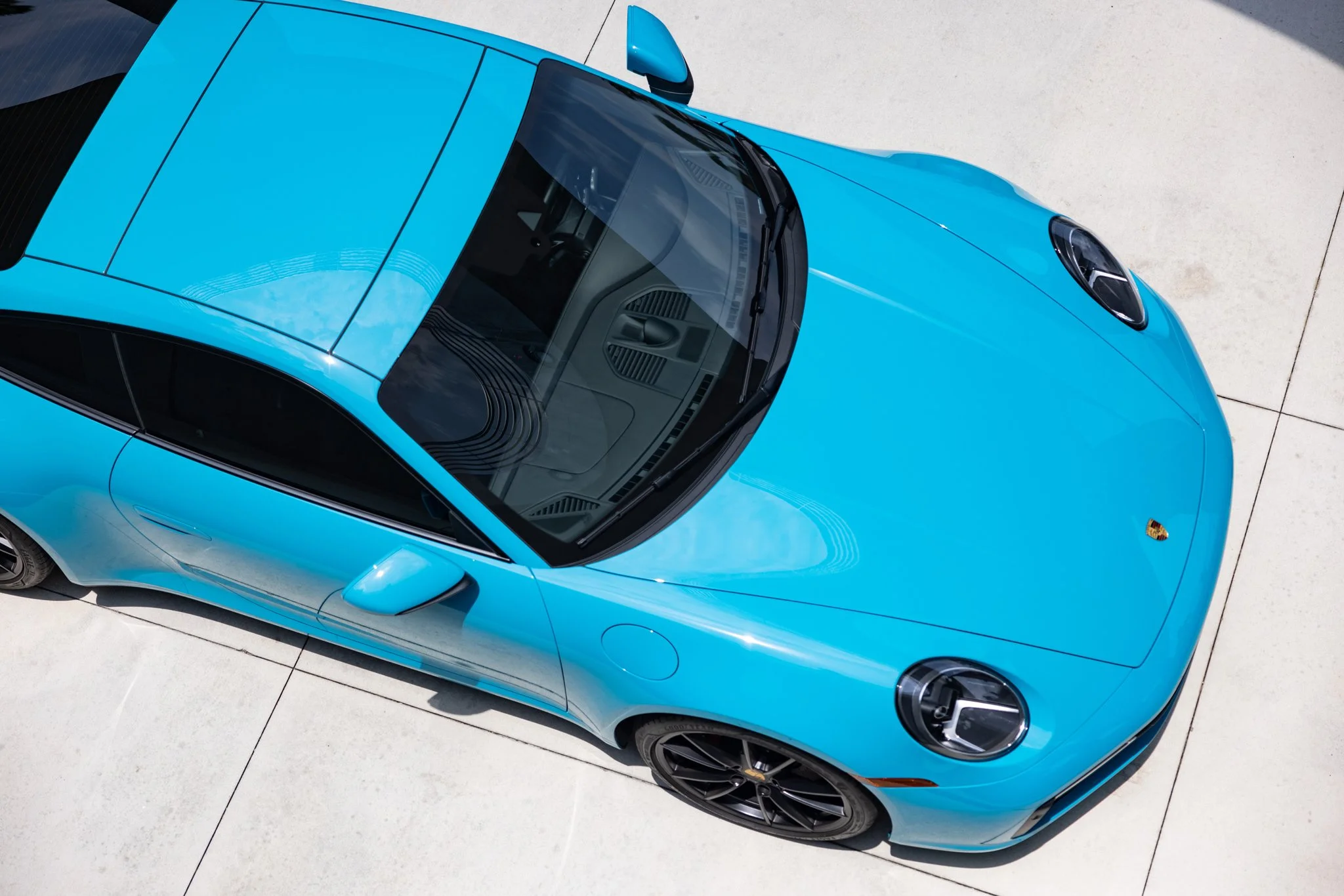 Top view of a bright blue Porsche sports car parked on a concrete surface.