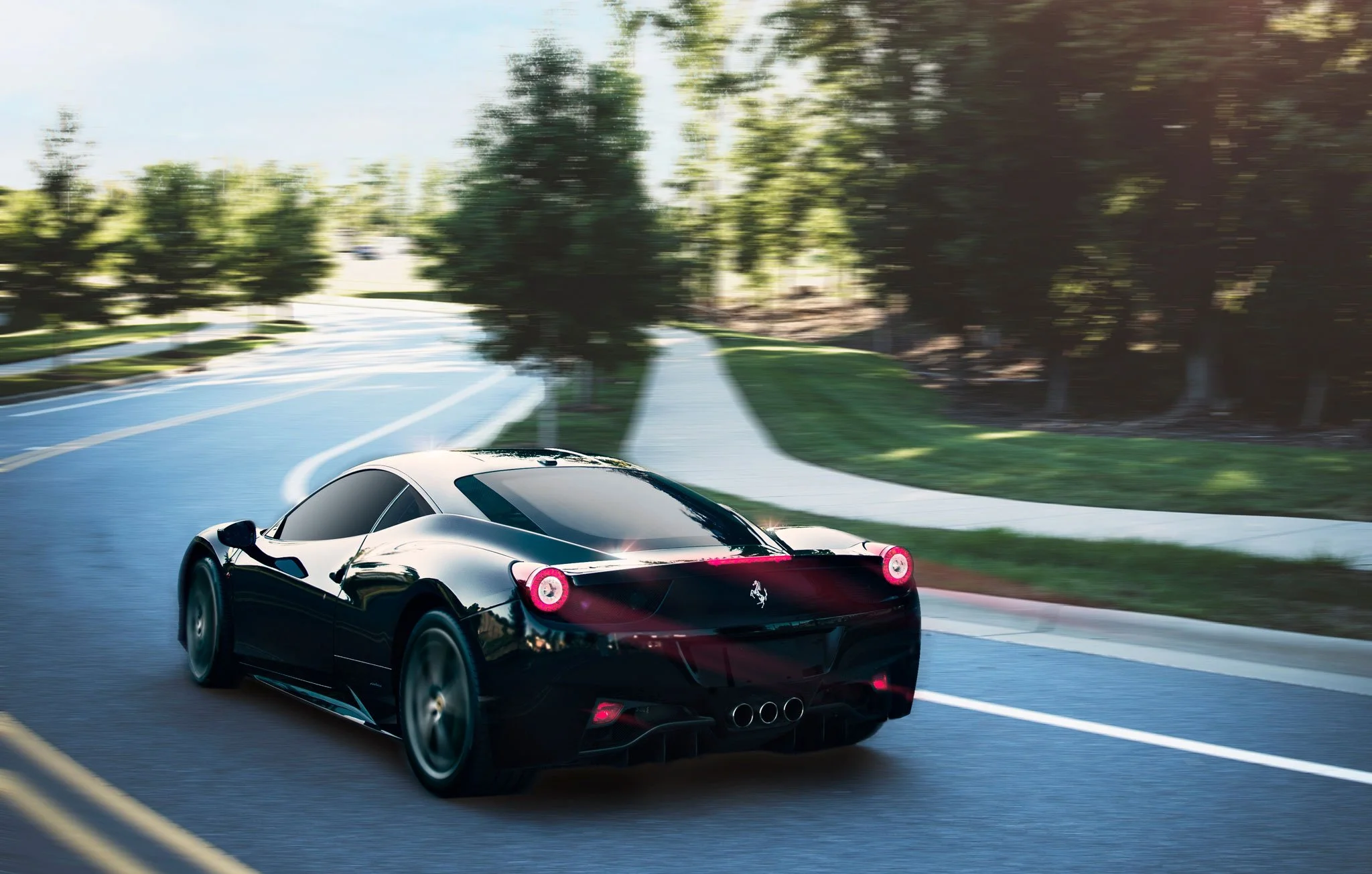A black Ferrari sports car driving on a curved suburban road surrounded by trees and greenery.