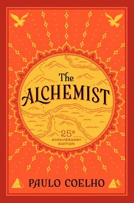 "The Alchemist" 25th Anniversary Edition book cover by Paulo Coelho, featuring a red and gold design with sunburst and bird motifs.