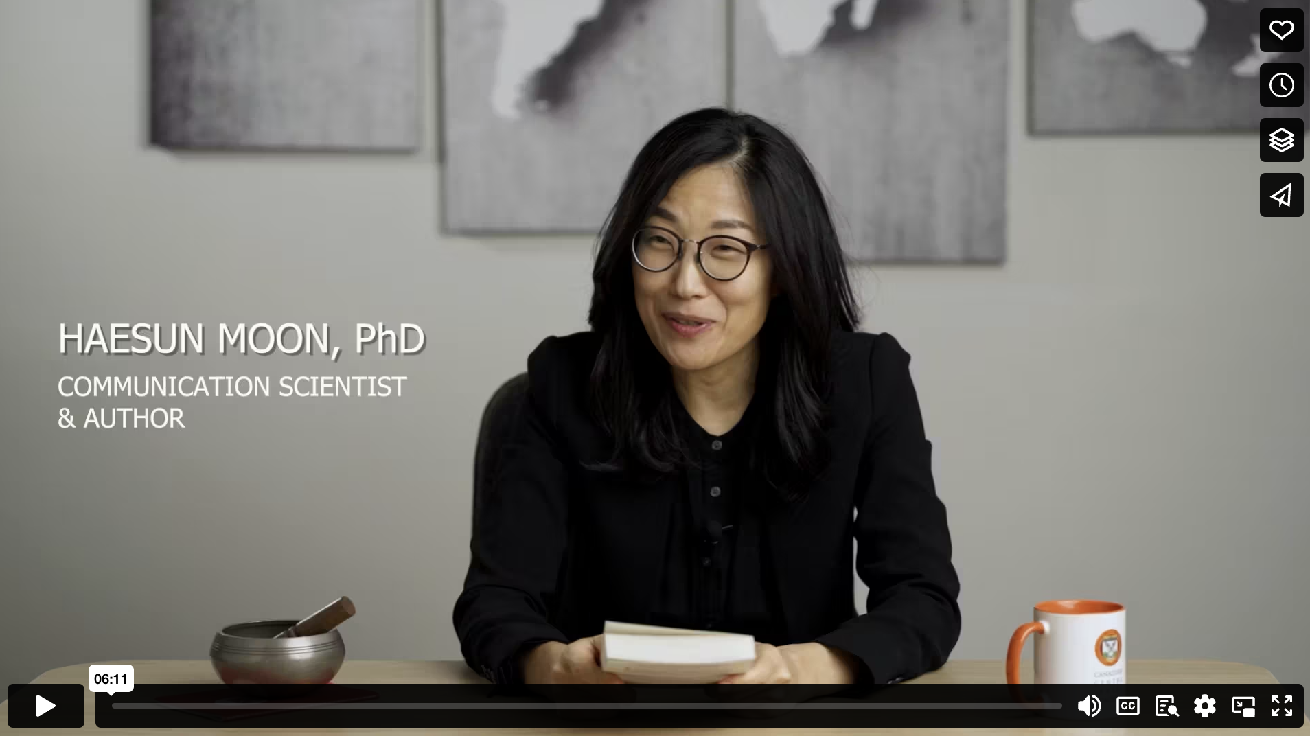 Person sitting at a table with a book and a mug, wearing glasses and a black shirt, with text overlay indicating name and profession.