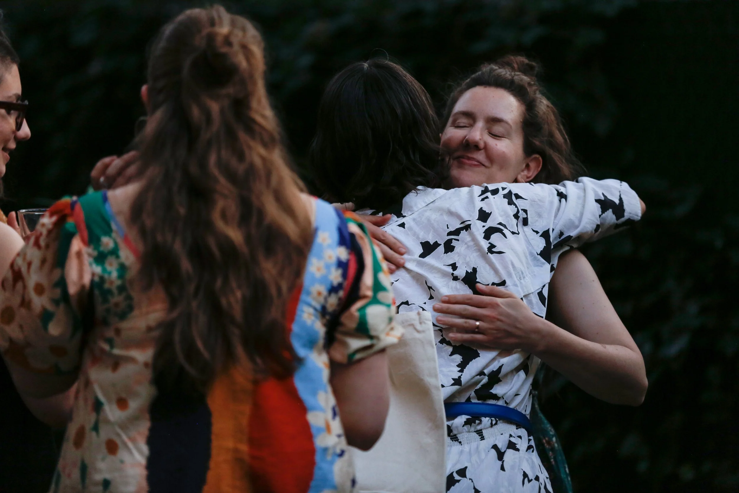 Two doulas sharing a warm embrace at a Baby Caravan community event, representing the peer support, collaboration, and sense of community doulas gain when joining the Baby Caravan doula collective in NYC.