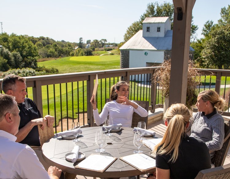    ArborLinks guests sitting on a patio overlooking the golf course   
