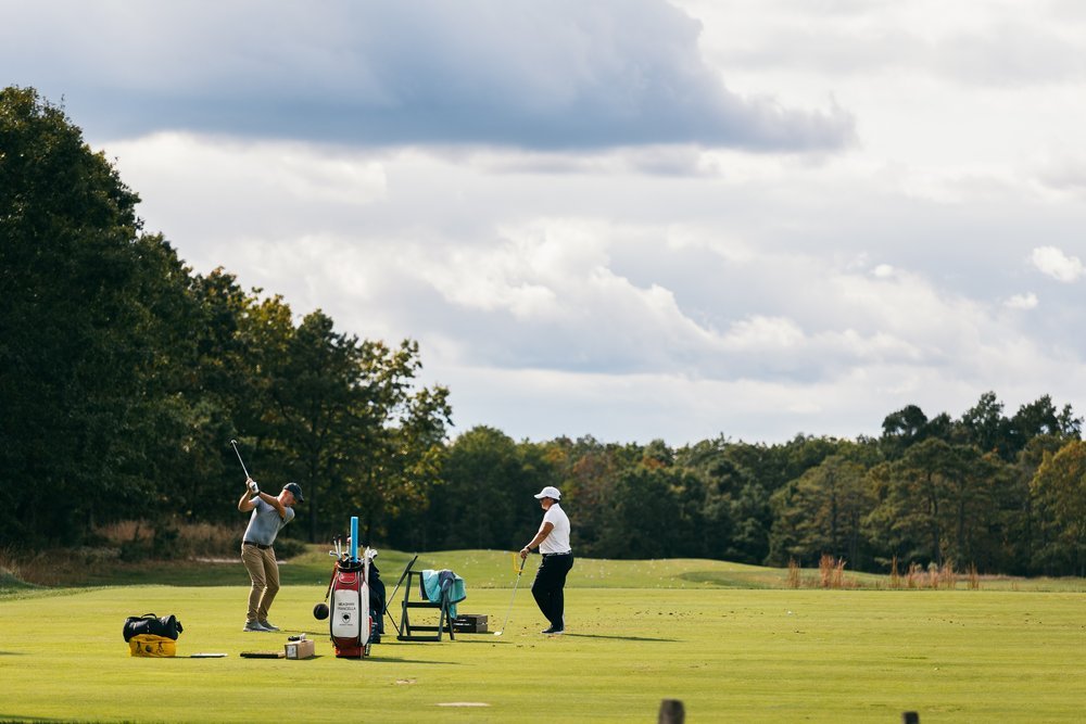  A golfer working with a golf instructor during the day.