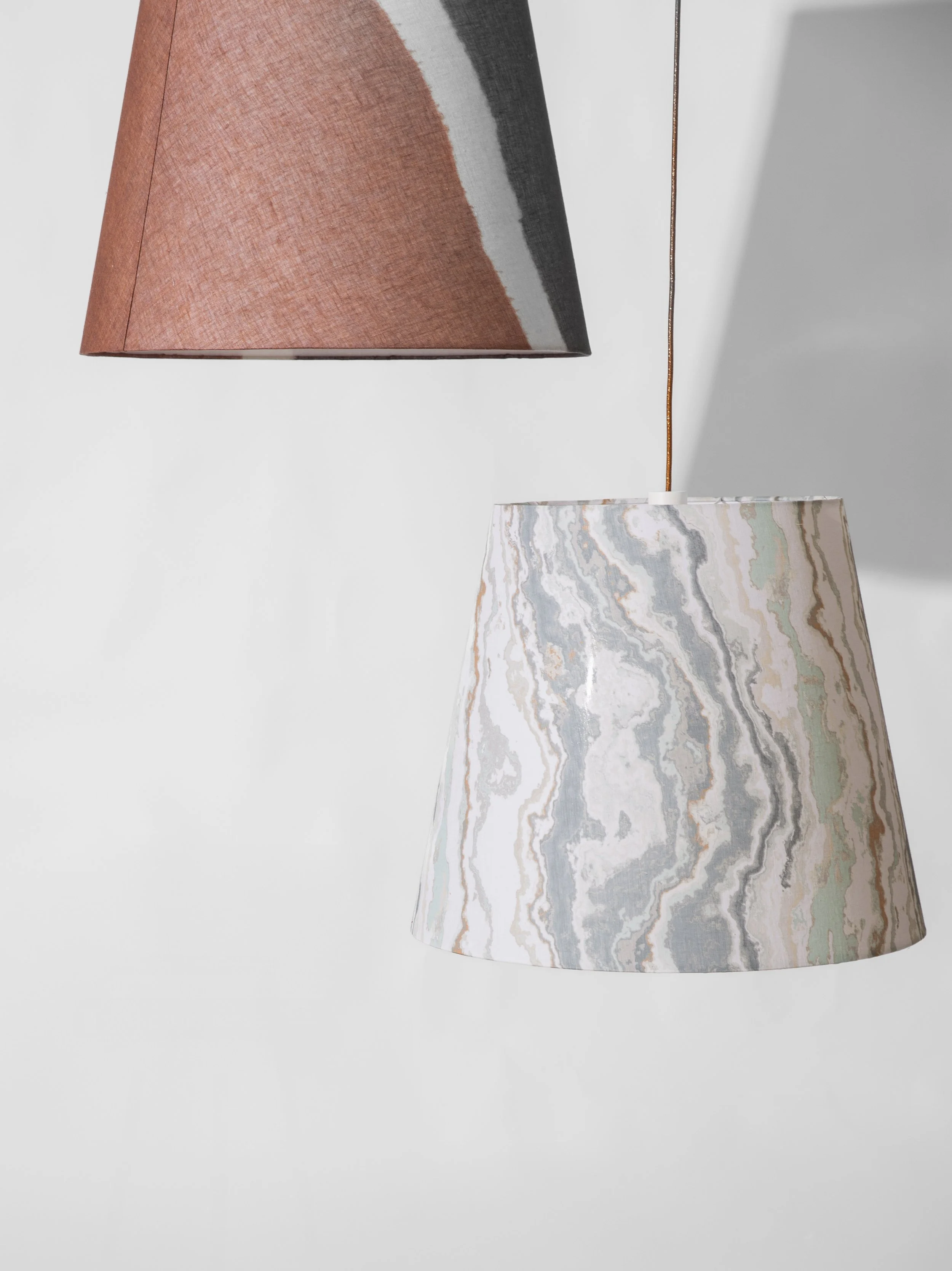 Due lampade a sospensione con paralumi in diversi disegni misti installate su uno sfondo bianco.