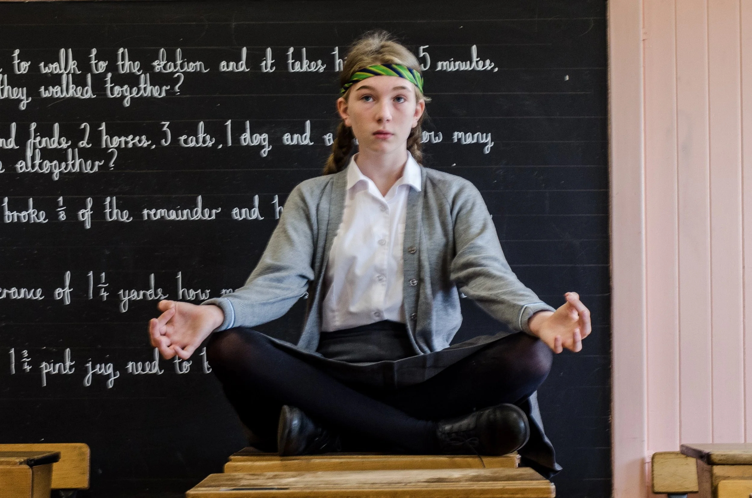 teen in classroom sitting on desk to mediate