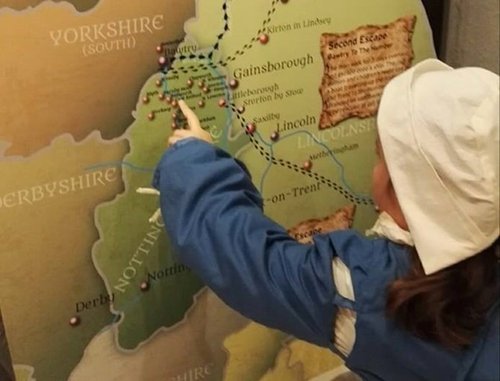 Child pointing at a historical map of England, featuring regions like Yorkshire, Nottinghamshire, Lincoln, Gainsborough, and notable locations such as Second Escape.