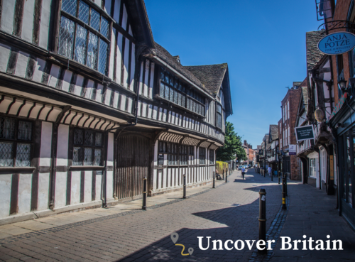 Empty Tudor-style street with shops and police station, sunny day in Britain.