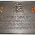 Plaque with a bust of Edward Winslow and an inscription detailing his role in Plymouth Colony, featuring a small flag and a crest at the top.