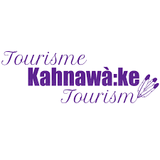 A landscape view of a lake with green hills in the foreground and mountains in the background under a cloudy sky.