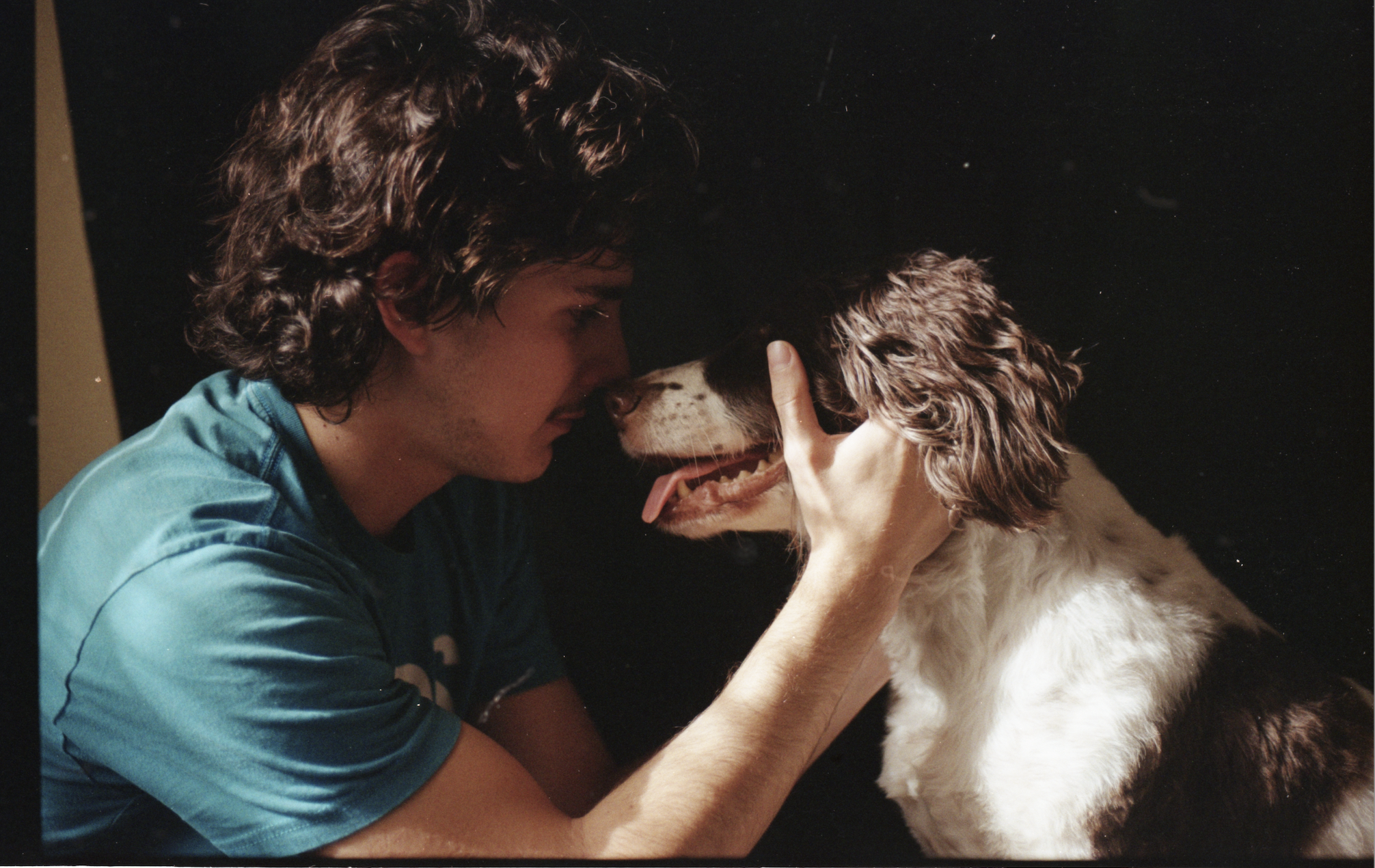 Color photograph of my brother holding our dog’s face close to his, tears streaming, capturing a raw, intimate moment of grief and farewell.