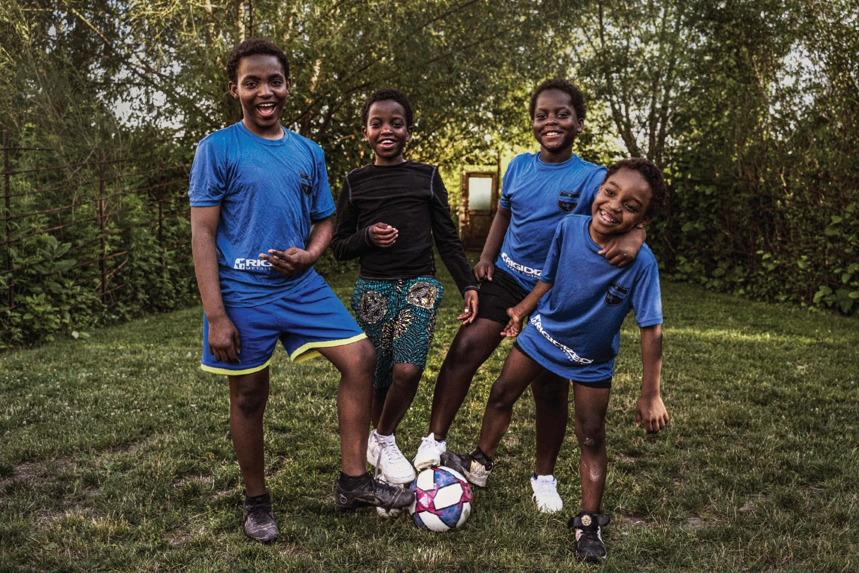photo of four boys from the Maendeleo Soccer Club with their feet on a soccer ball. by Mark Dellas