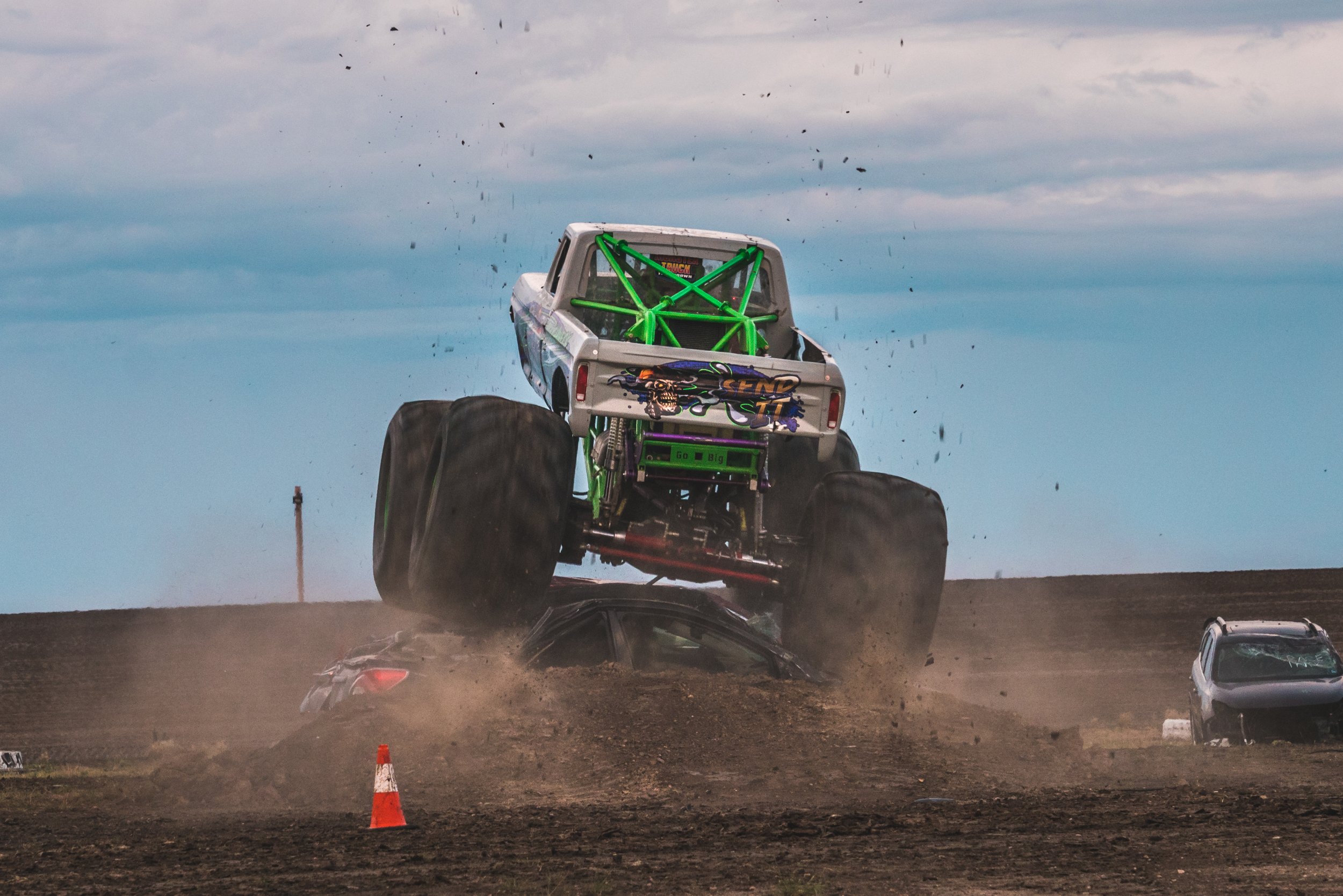 Monster truck crushing a car with dirt flying