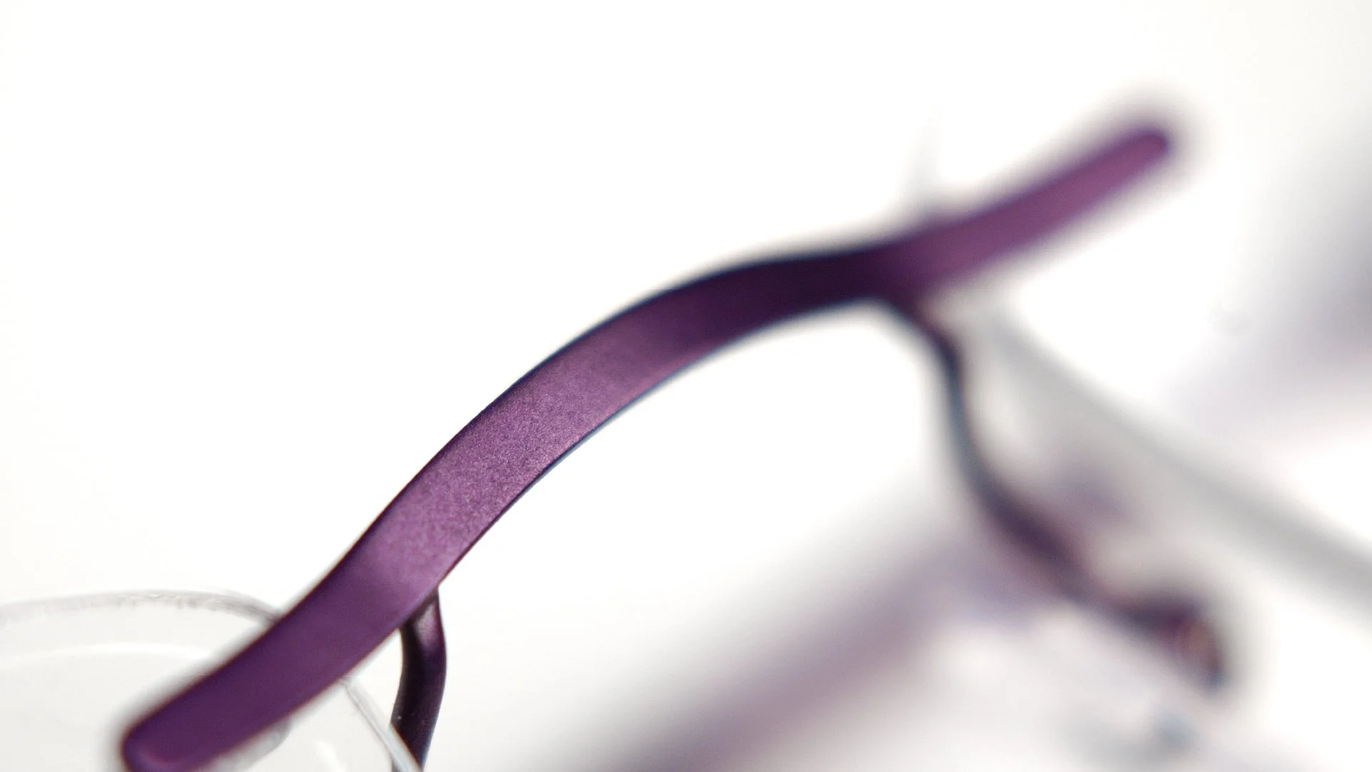 Titanium eyewear design detail for Kingsight, showing a close-up of a purple frame element and material finish.