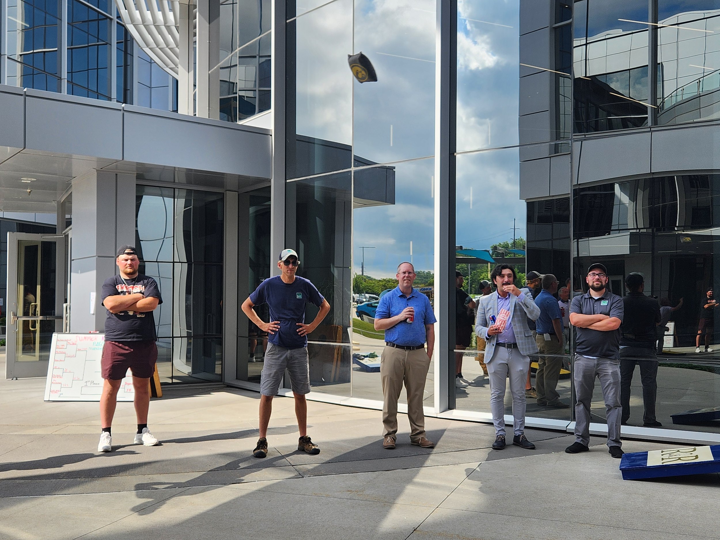 Five men standing outside a modern glass building looking at the camera.