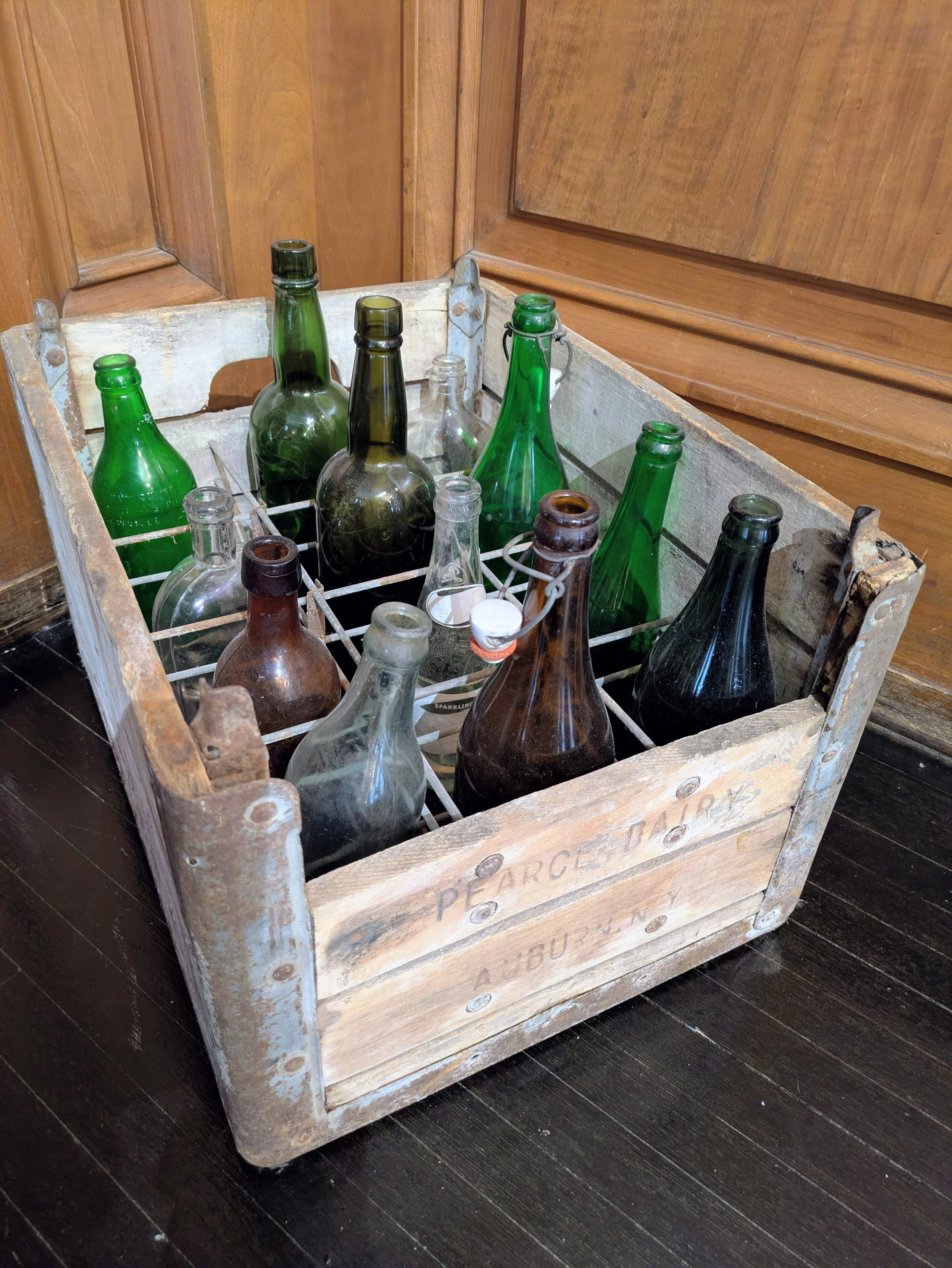 An old wooden barrel filled with glass bottles.