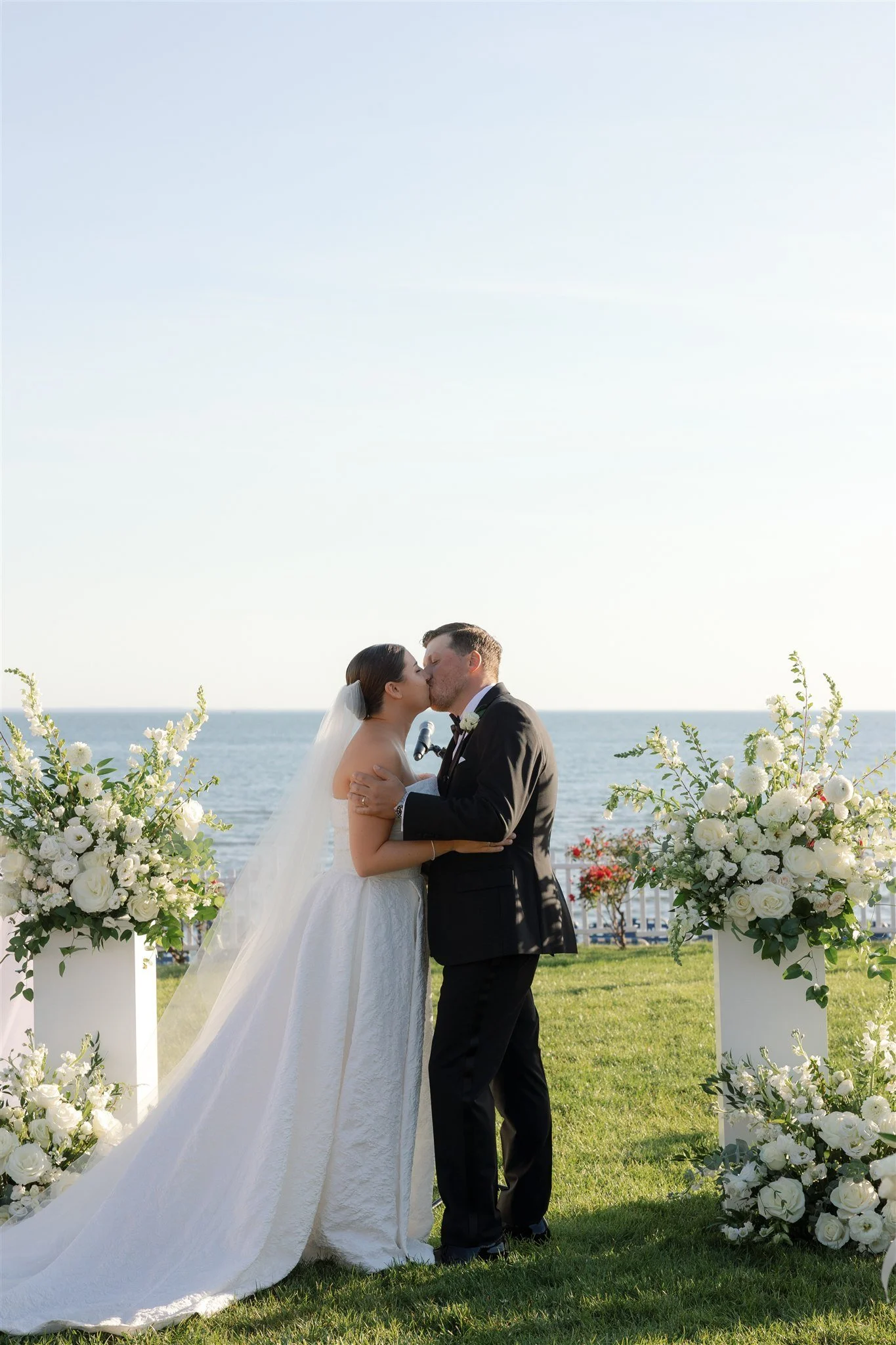 Outdoor ceremony photographed under a clear, hazy-blue summer sky at Water’s Edge.