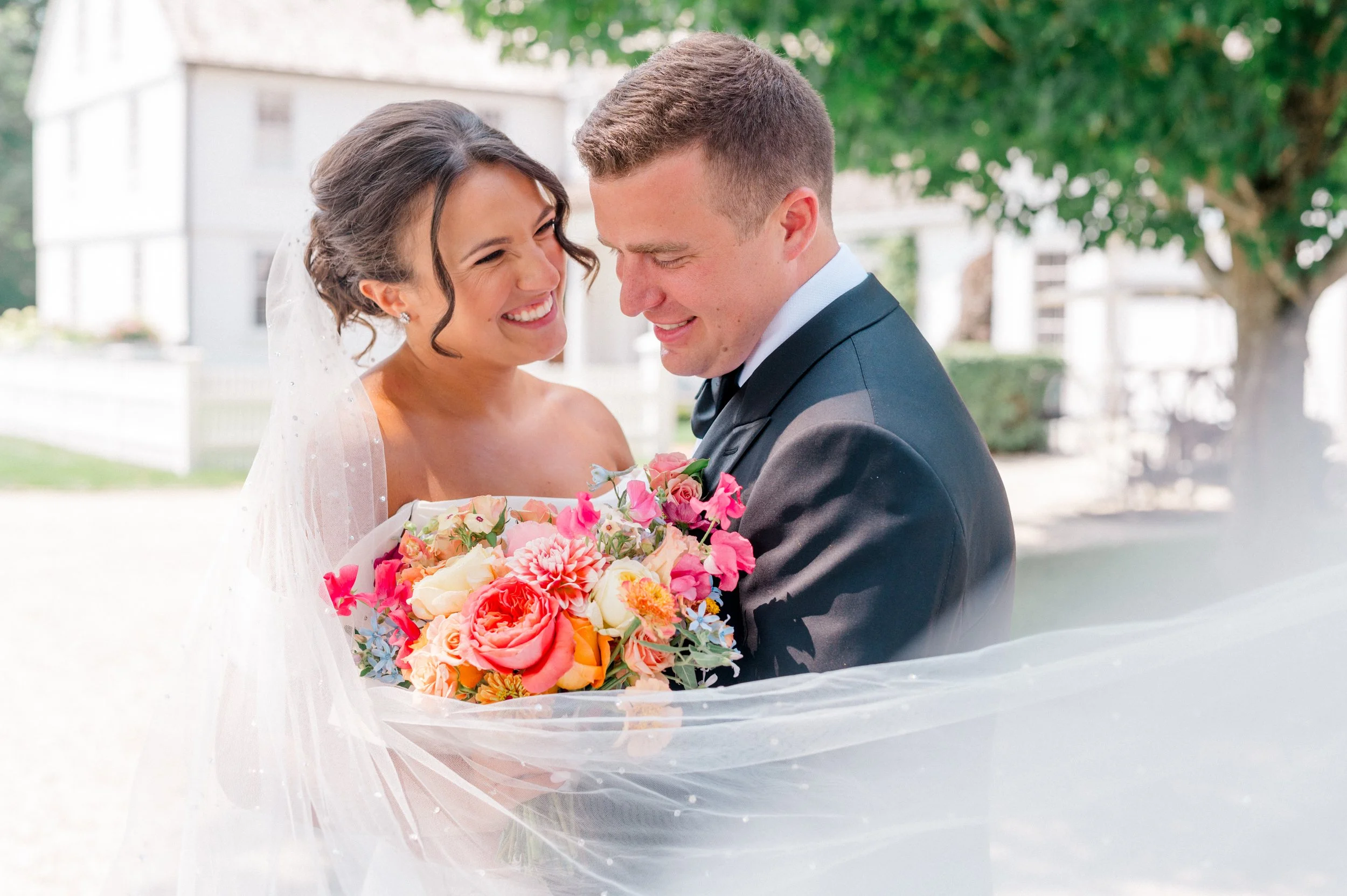 Bright bridal bouquet with coral and fuchsia dahlias, butter-yellow roses, and magenta sweet pea.