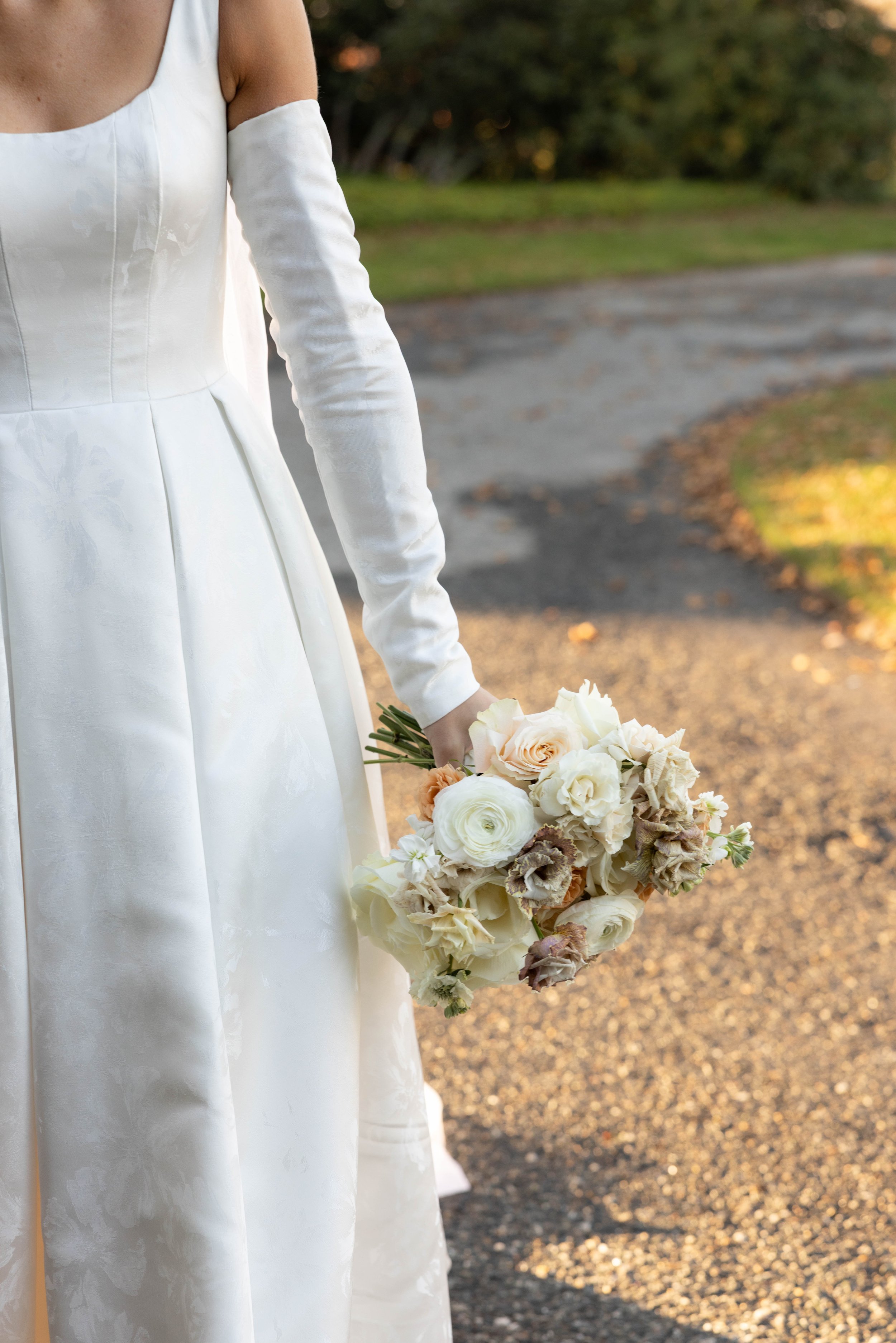 Bride standing in the formal gardens at Eolia Mansion with a lush neutral-toned bridal bouquet.