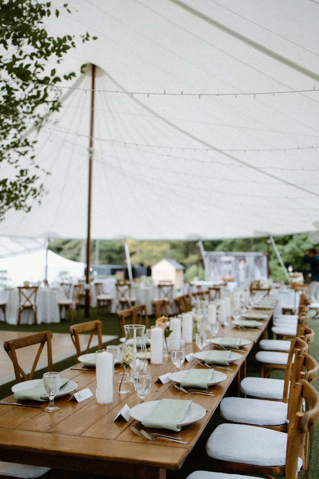 Long reception tables beneath a white sailcloth tent styled with airy garden-style wedding flowers.