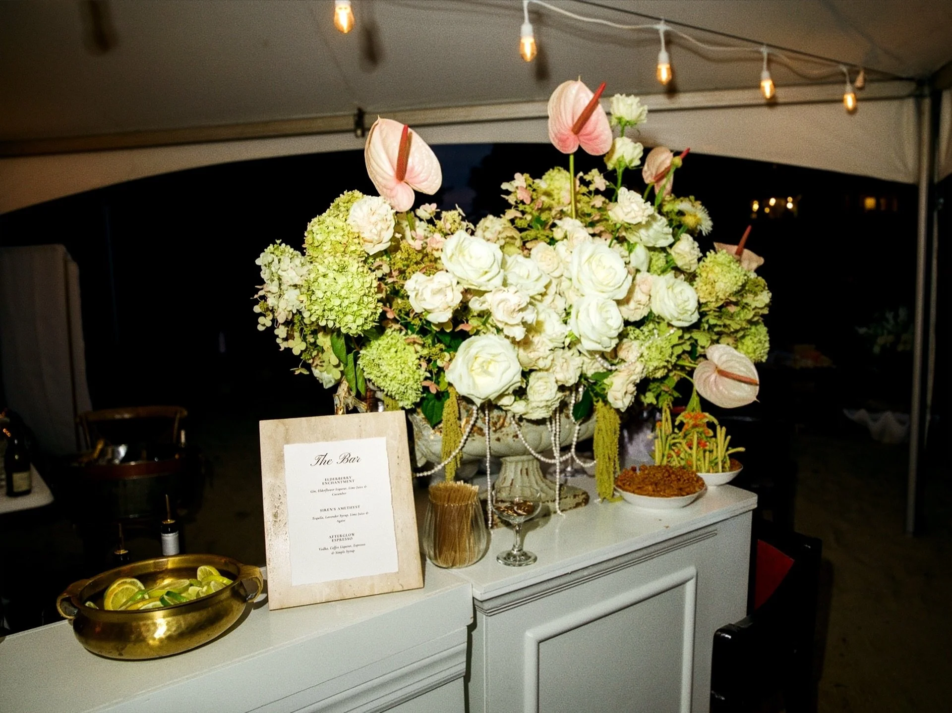 Vintage urns draped in pearls filled with hydrangea, garden roses, and tropical anthurium on bar display, First Blush Floral Design + Planning