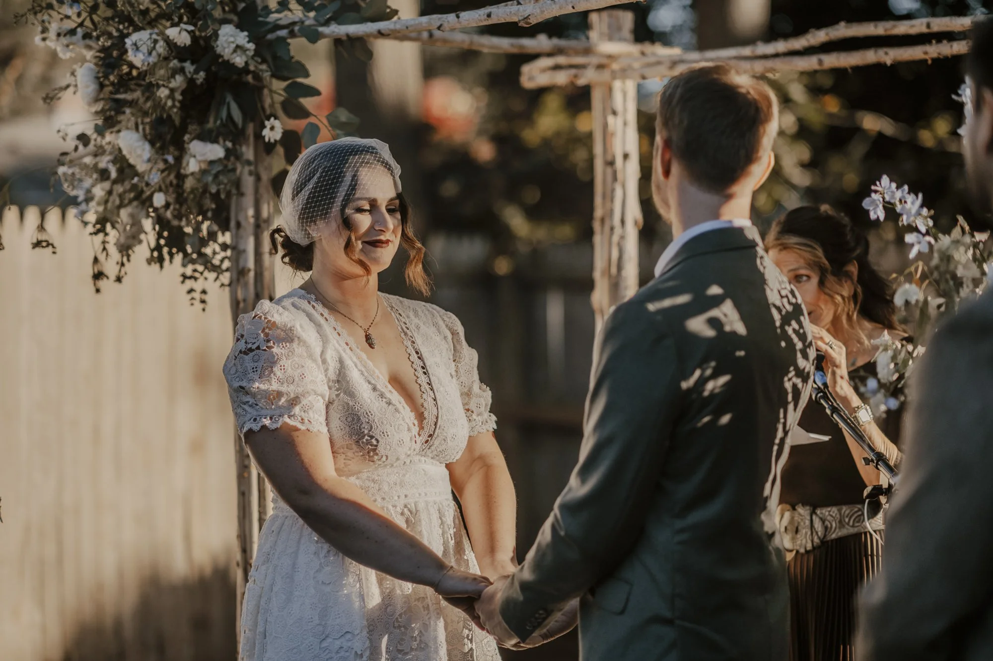 Close-up of white and blue flowers cascading from the corner of a birch-pole wedding arbor