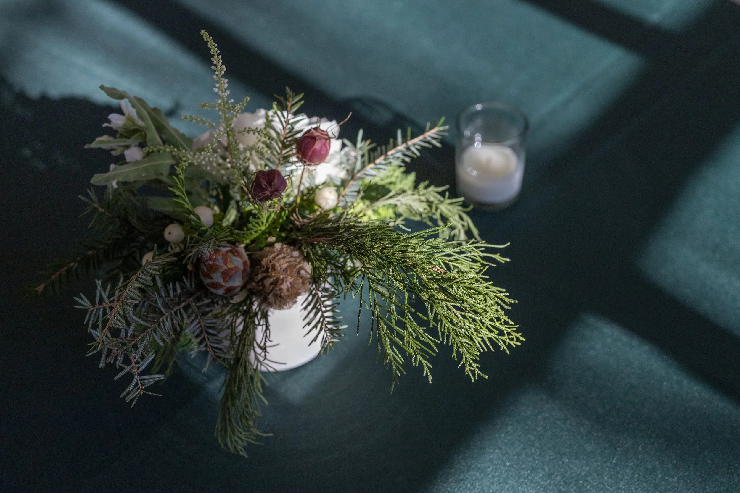 Close-up of pine cones and white hypericum berries tucked into an evergreen centerpiece