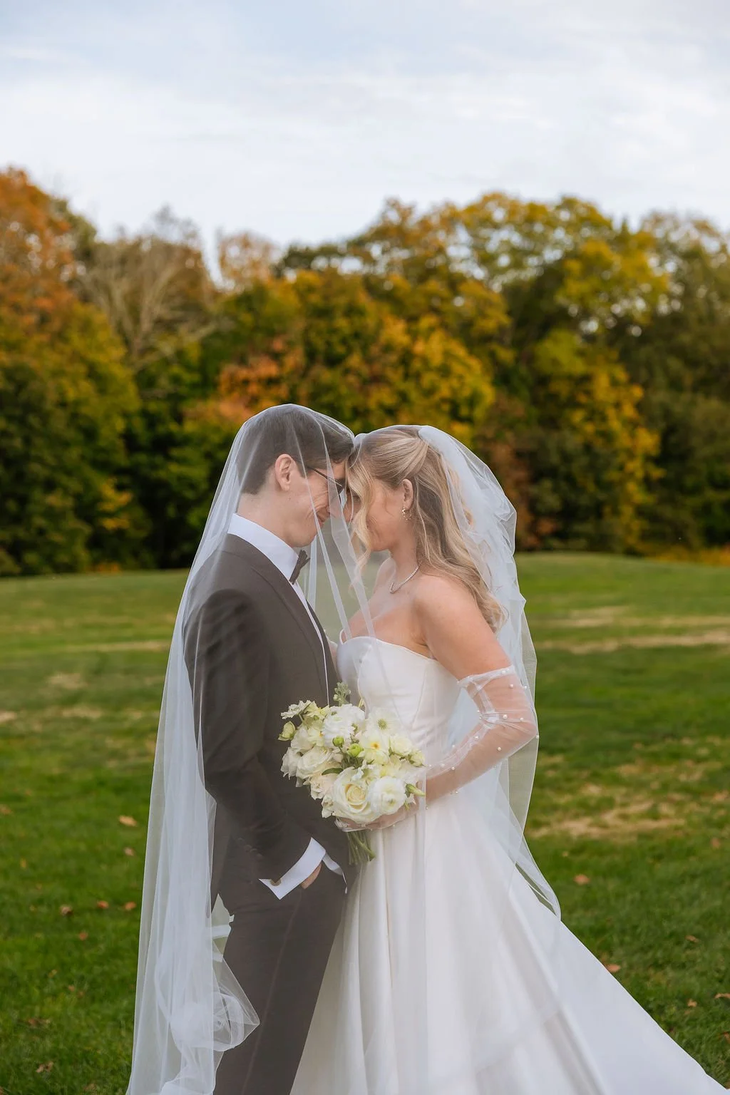 Bride holding butterfly ranunculus and cottage rose bouquet wearing pearl dotted gloves at Waveny House wedding