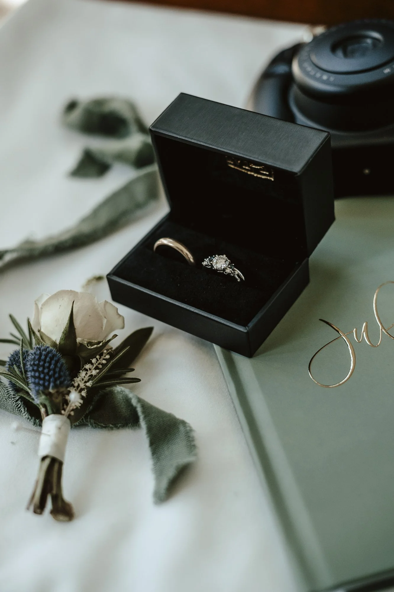 White spray rose and blue thistle boutonniere and ring detail shot.