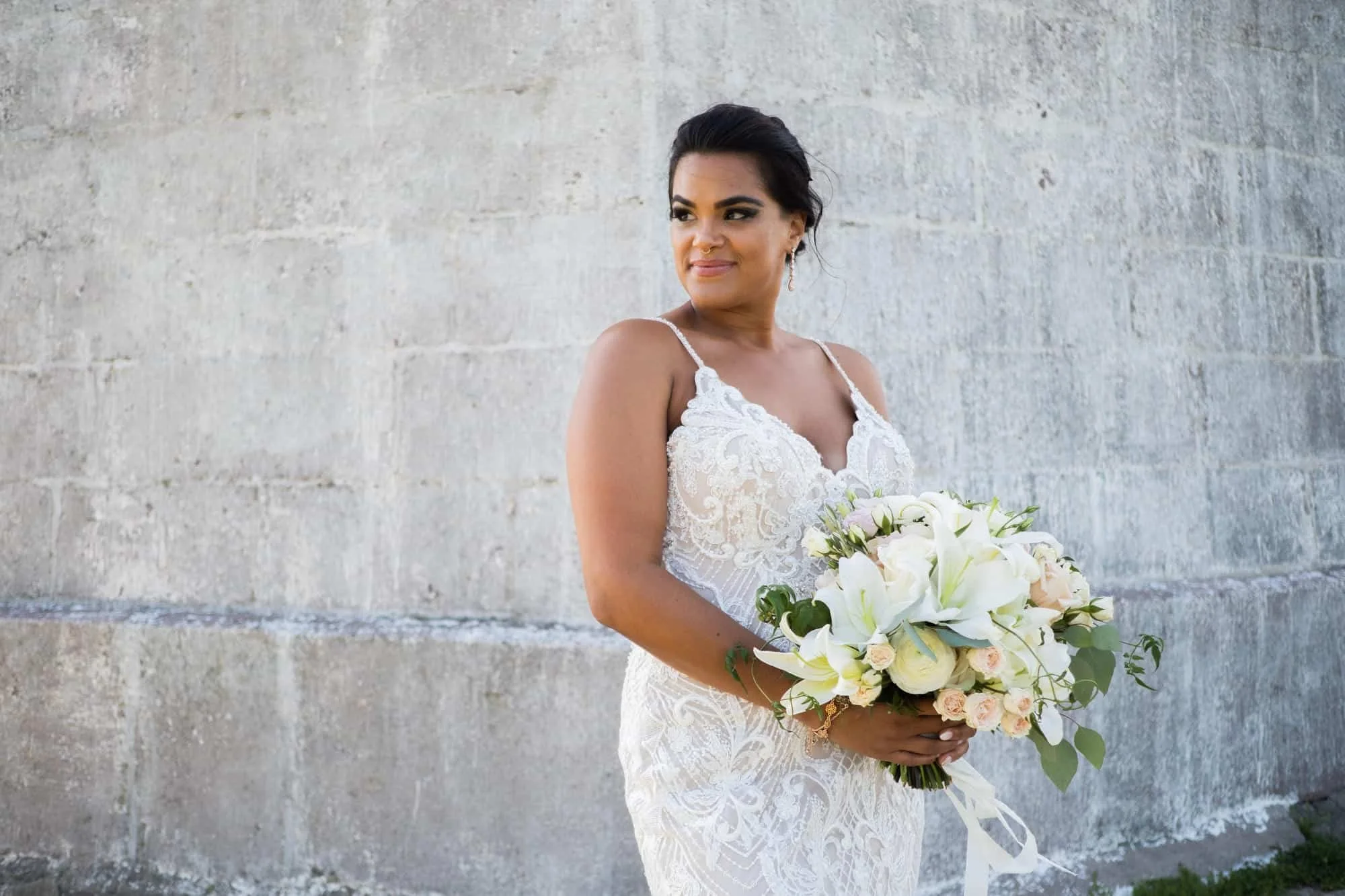 Close-up of a white lily bridal bouquet with lisianthus, sweet pea, spray roses and trailing jasmine vine by a Connecticut wedding florist