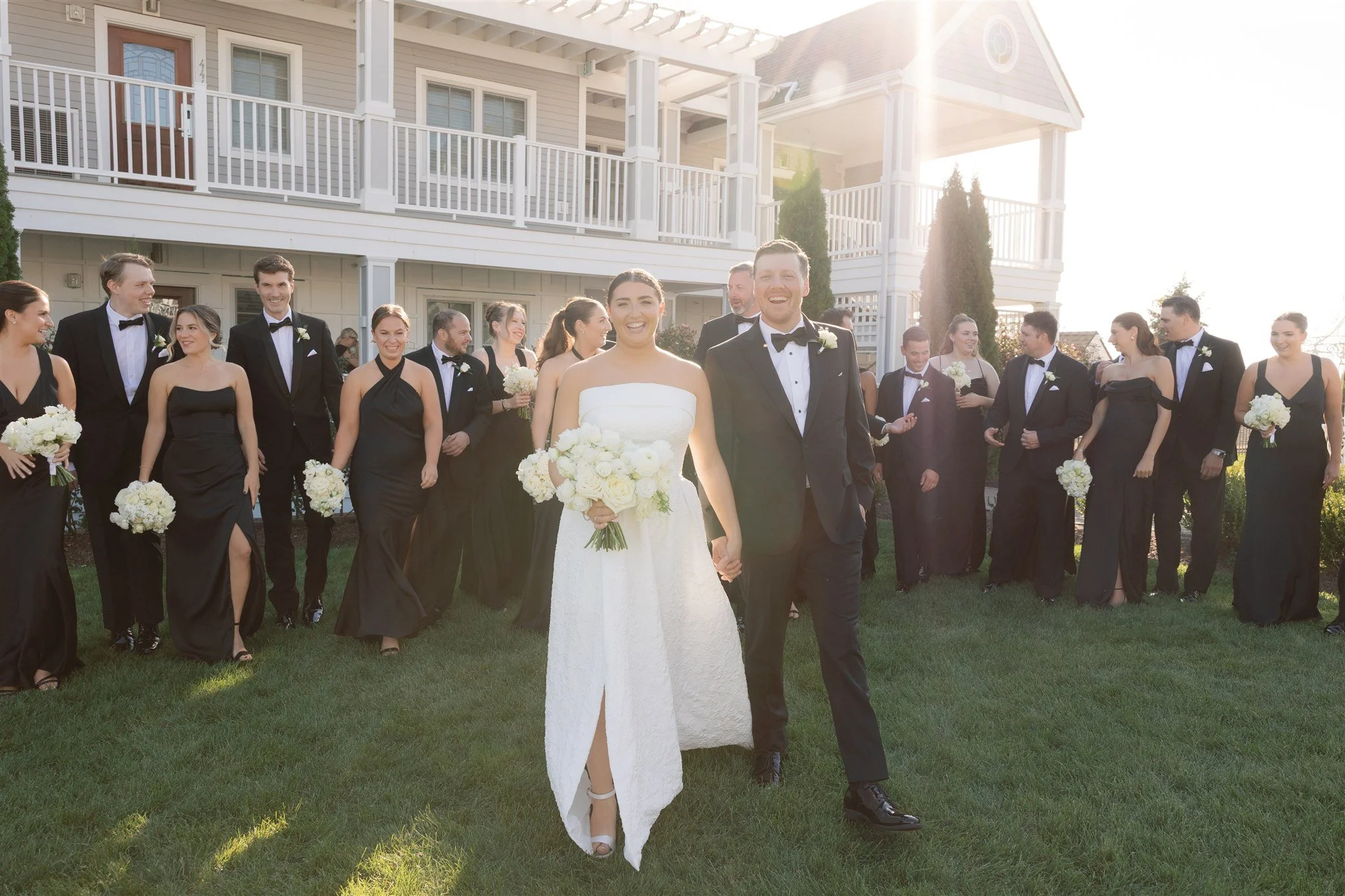 Bridesmaids holding petite posy bouquets of white roses, lisianthus, and spray roses for a cohesive all-white bridal party.