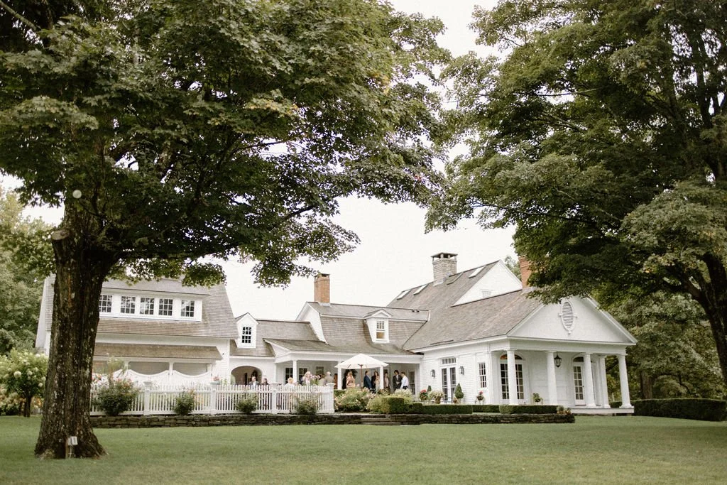 Historic white estate surrounded by lush trees and gardens at Smith Farm Gardens in Connecticut.