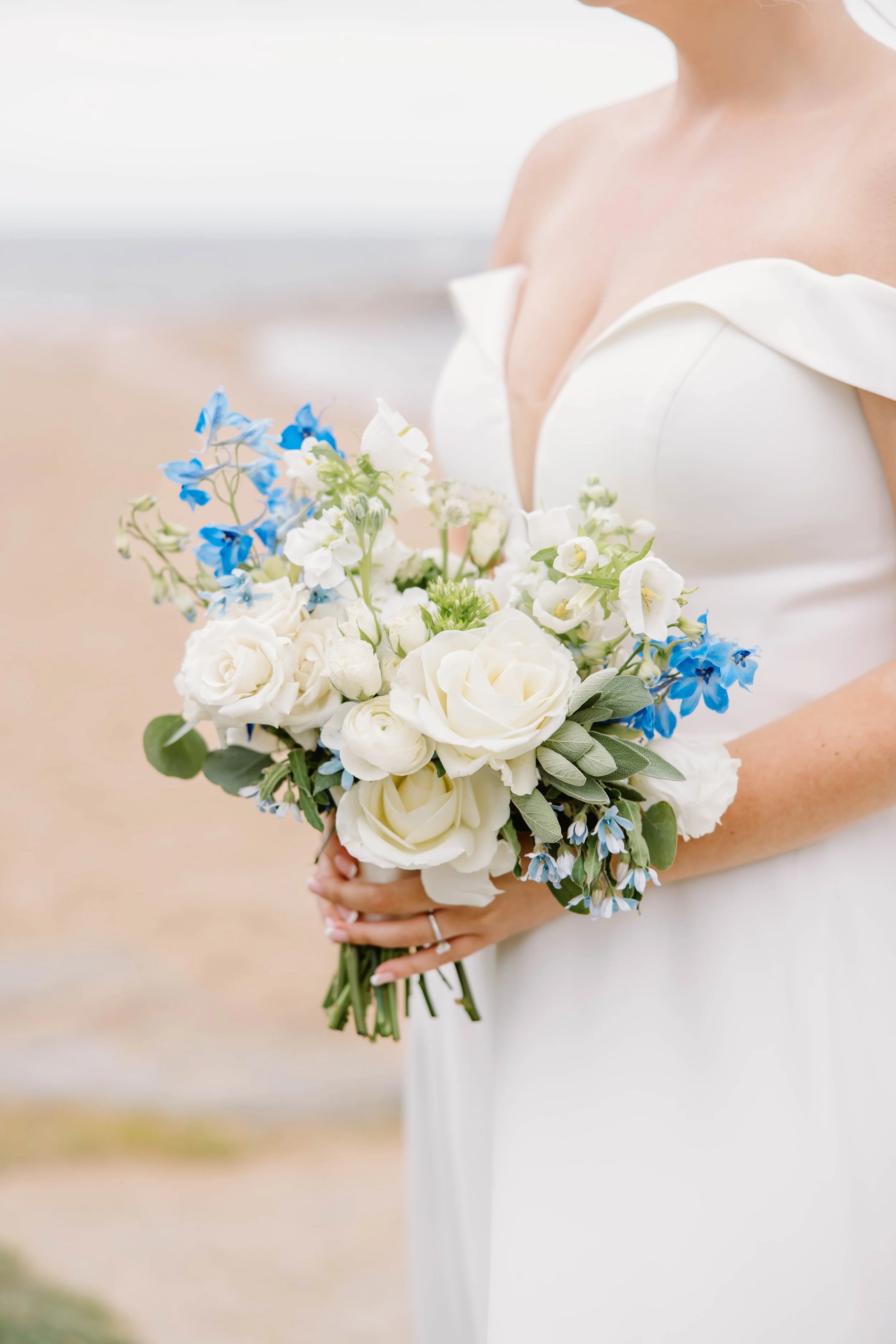 Lush bridal bouquet of blue hydrangea, white roses, and local dahlias tied with ivory silk ribbon.