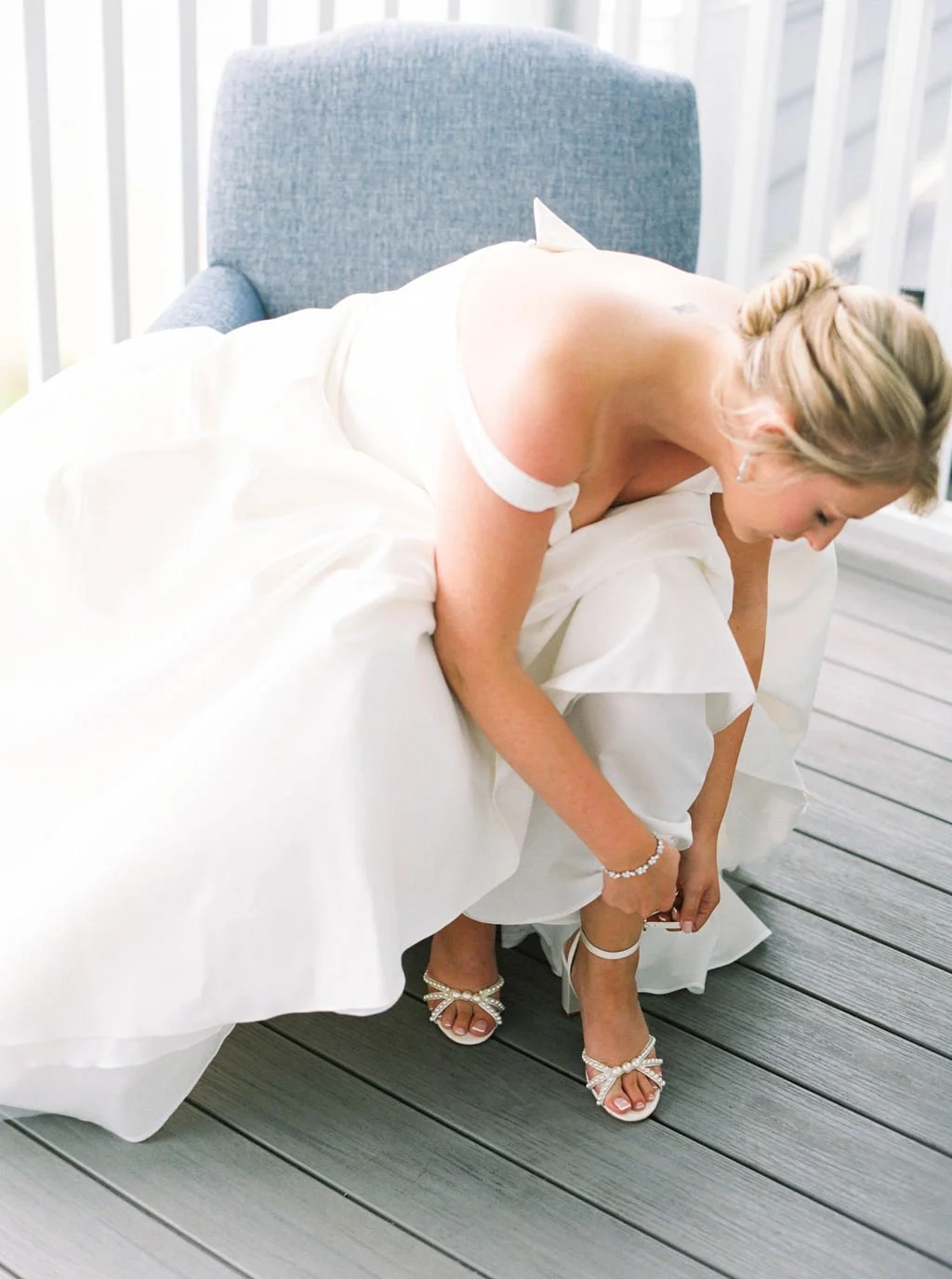 Elegant bridal shoes photographed with bouquet and soft blue stationery elements.