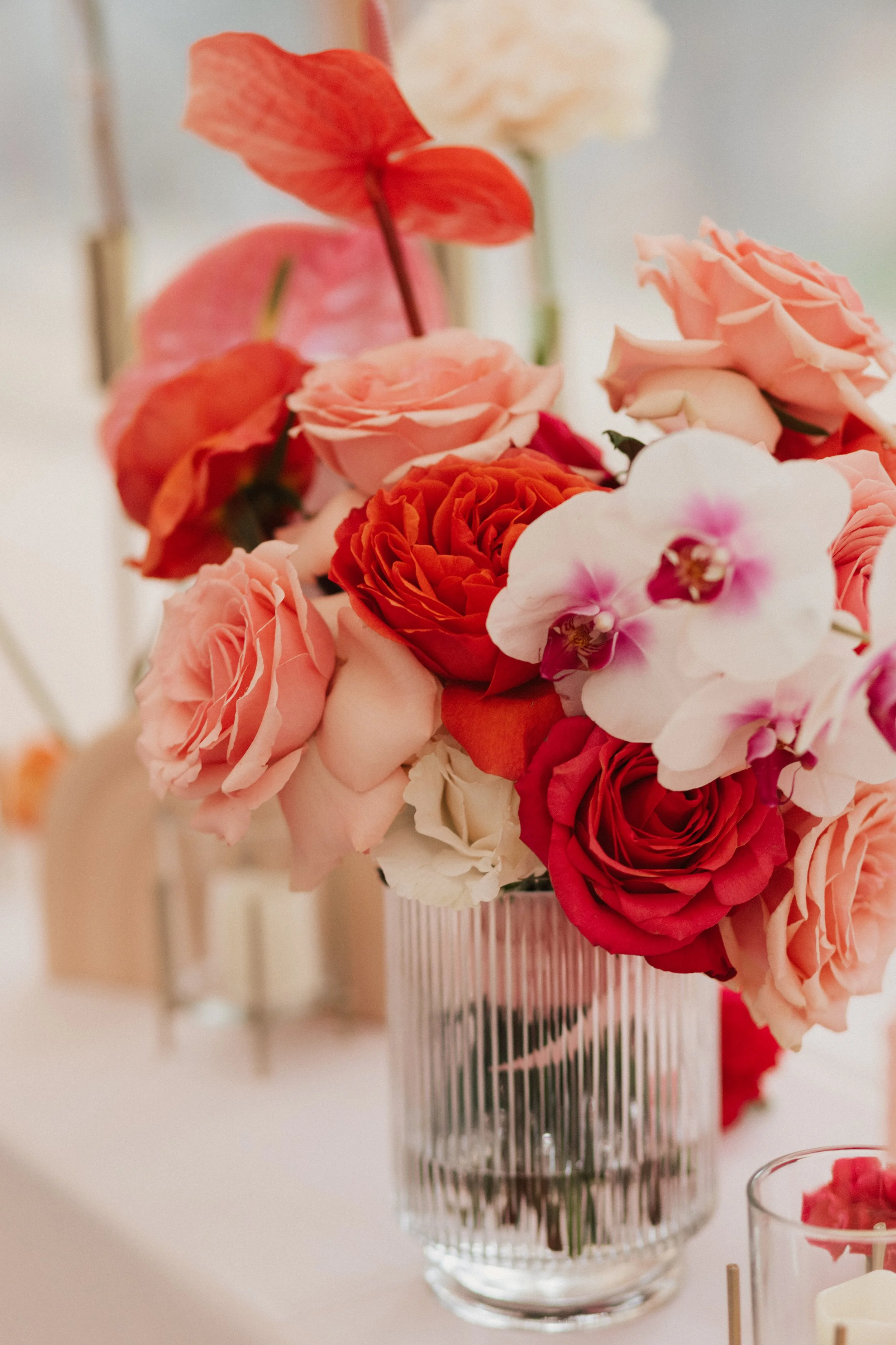 Stylish bride’s bouquet featuring coral roses, pink anthuriums, and cascading phalaenopsis orchids.