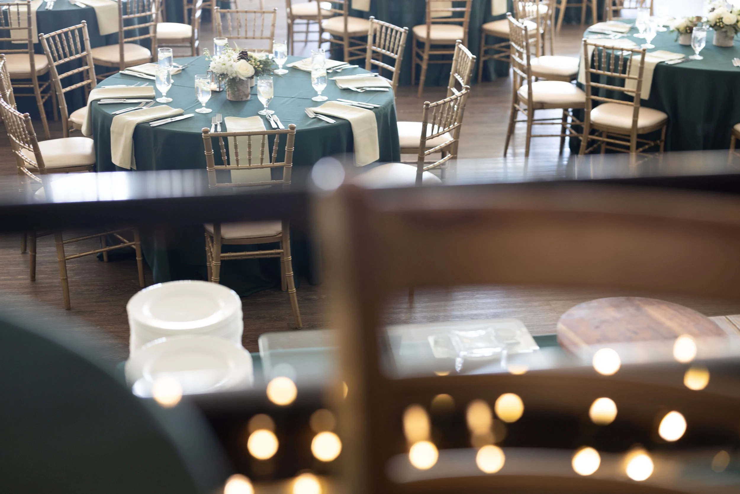 Reception room at The Inn at Longshore set for a winter corporate event with round tables, deep green linens and white evergreen centerpieces