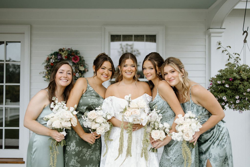 Bridesmaids holding airy white garden-style wedding bouquets with soft seasonal greenery.