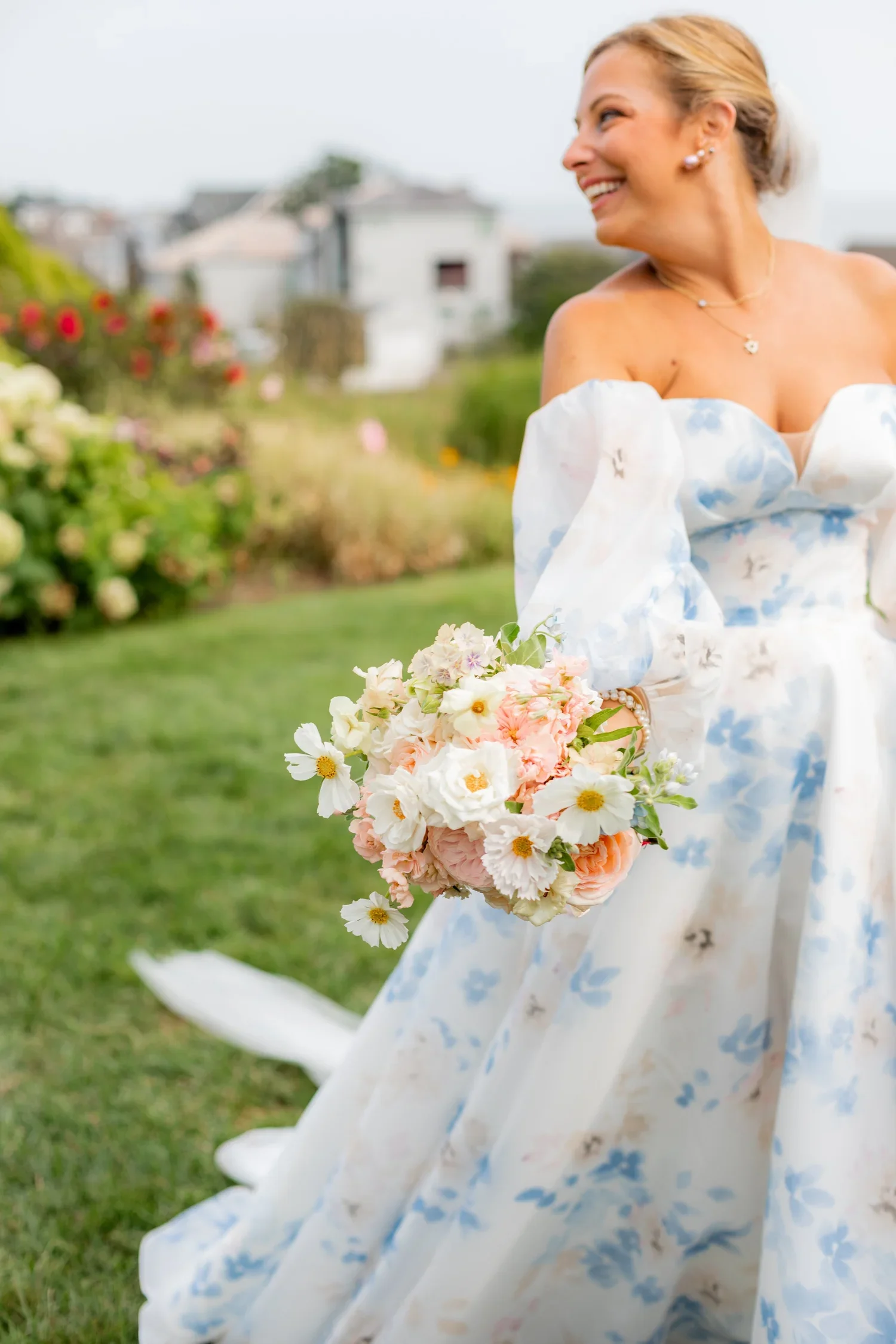 Springtime bridal bouquet with soft whites and blushes, held by bride in floral print grown at Waters Edge with First Blush Weddings