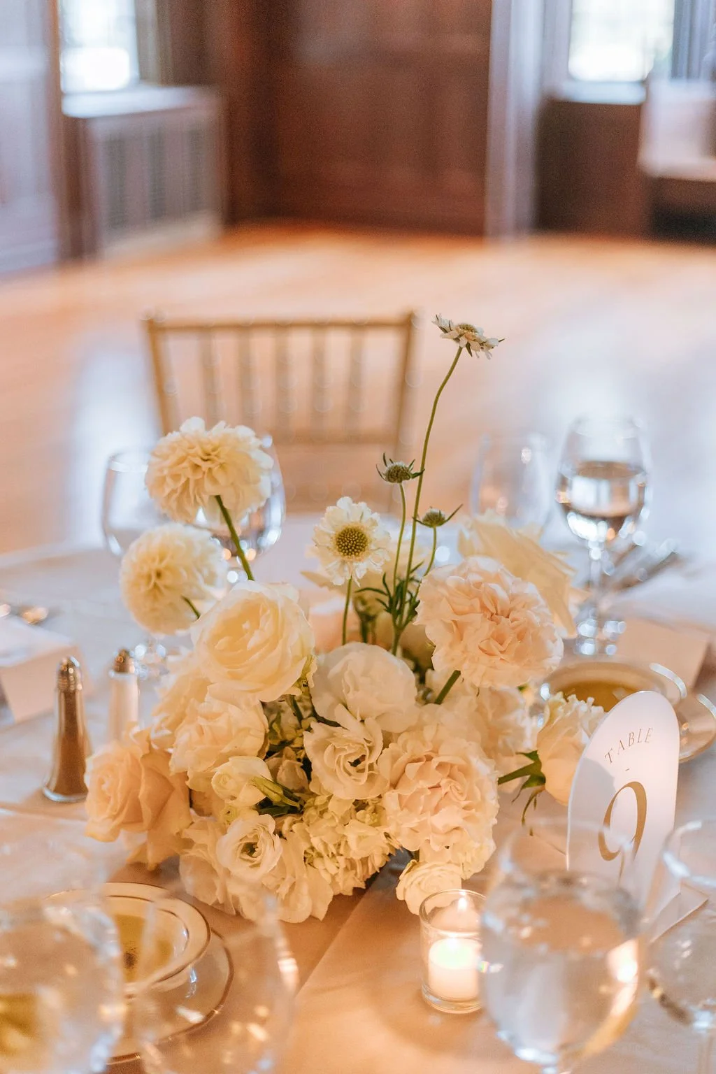 Candlelit reception tables with neutral floral mounds at Waveny House wedding