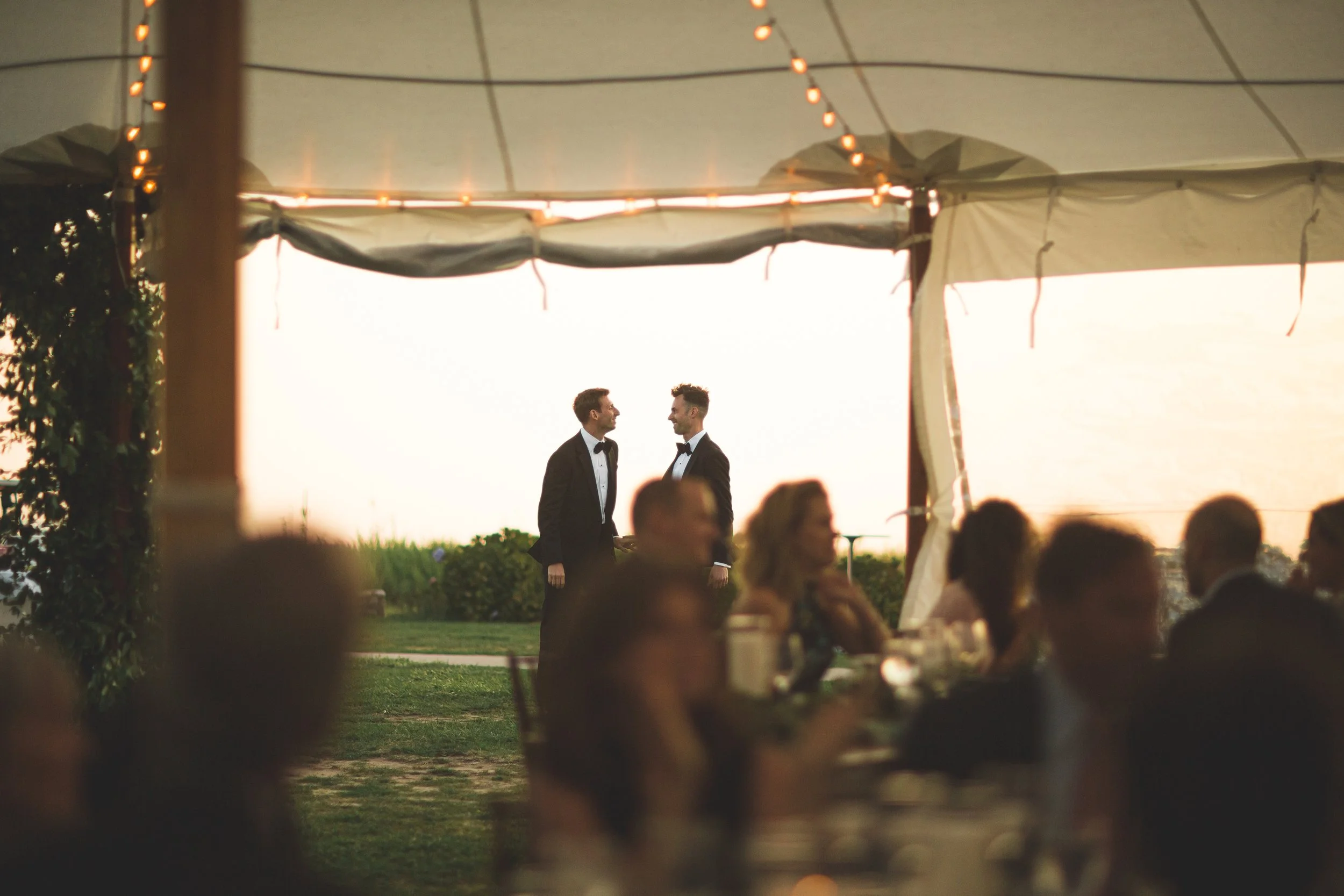 Guests gather beneath a sunlit sailcloth tent for a reception overlooking the Sound at a private Saybrook Point residence.